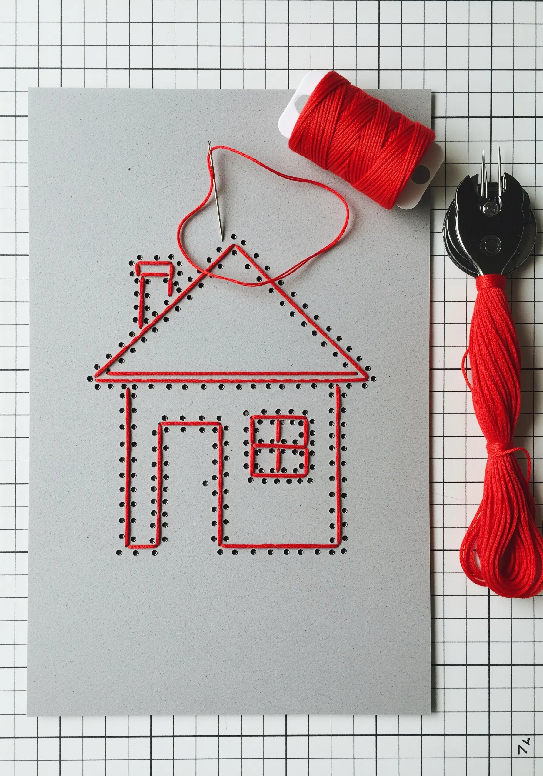A simple house outline created with red embroidery floss stitched through pre-punched holes in grey cardstock.