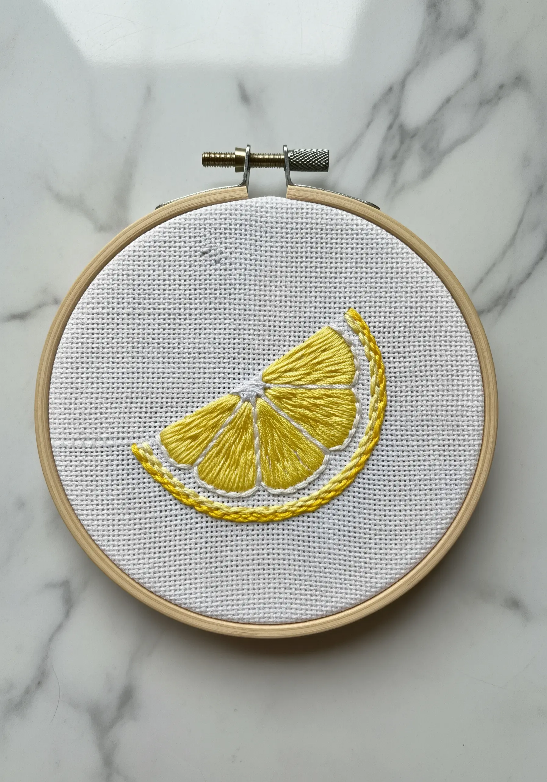 A lemon slice with satin-stitched segments, each defined by a subtle outline.