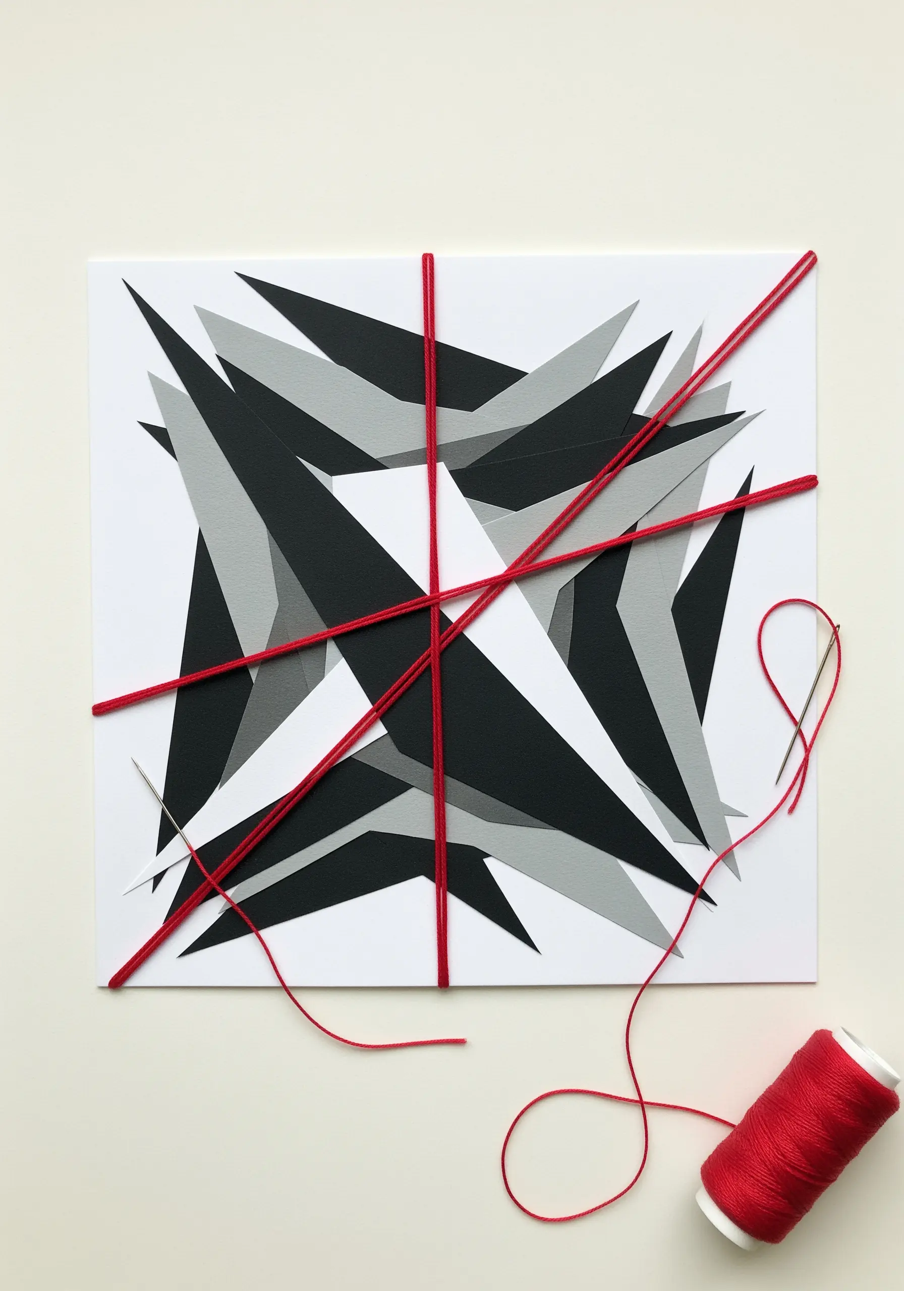 An abstract geometric paper collage with bold red threads stretched across the surface.