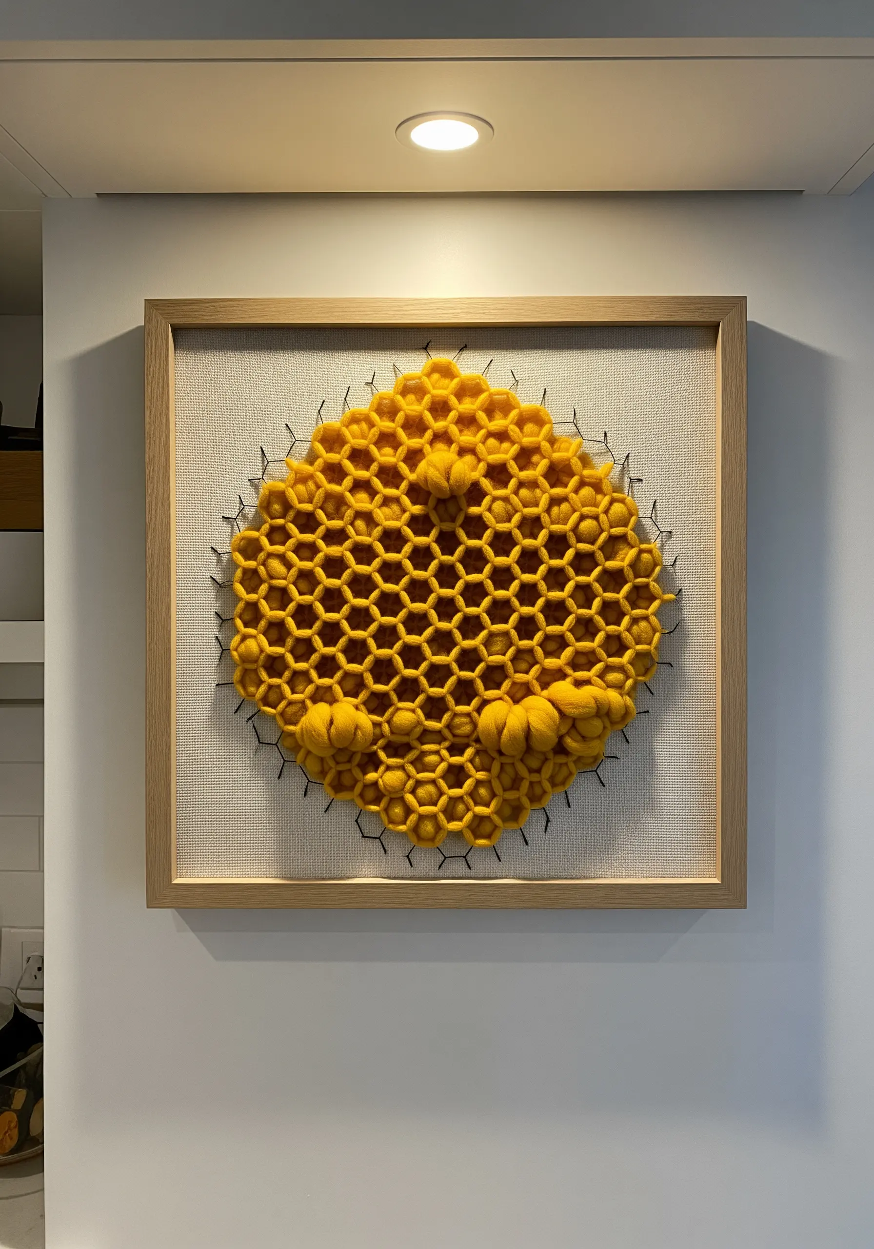 Framed wall art of a yellow honeycomb structure made from woven chunky yarn, with textural details.