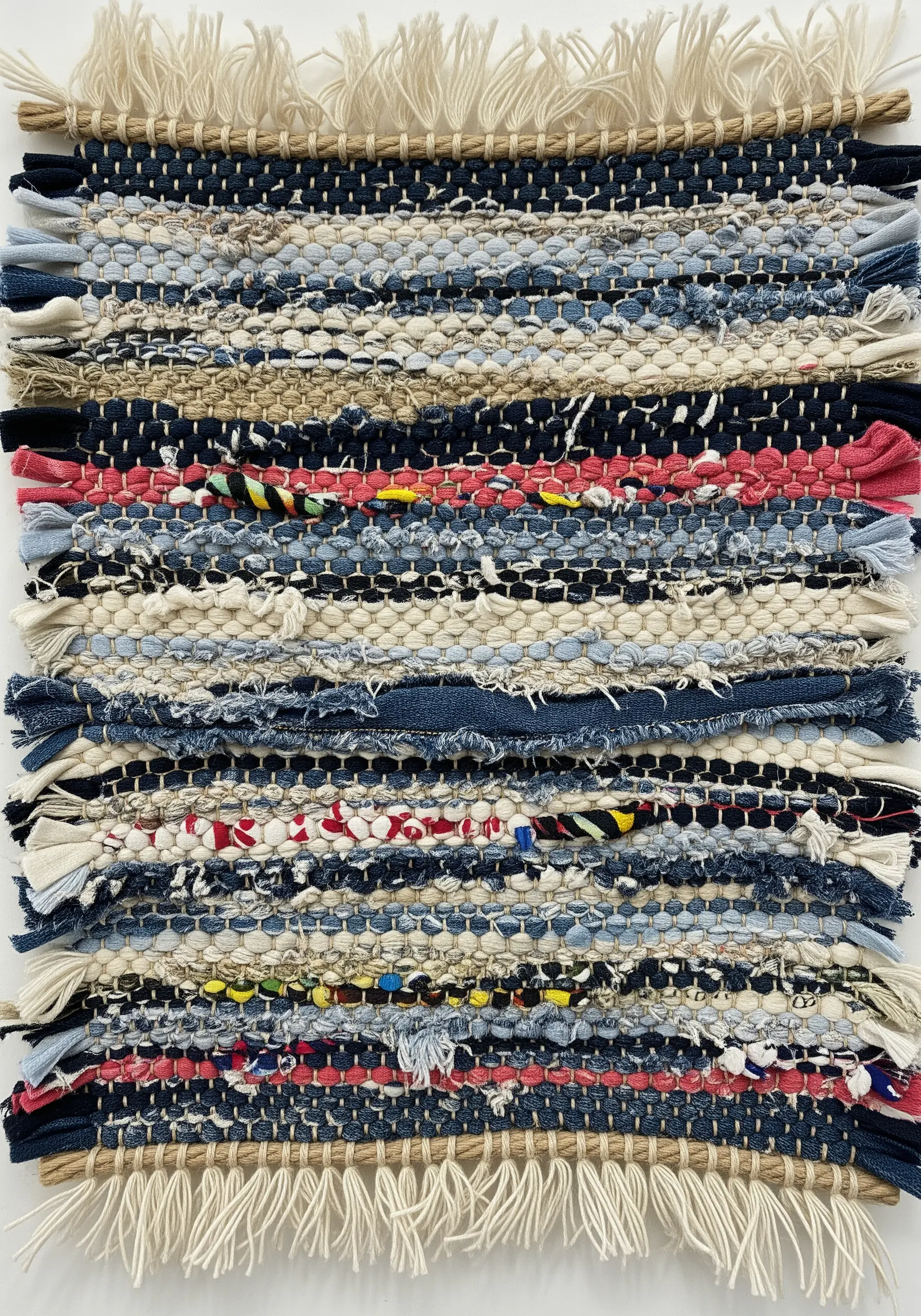 A woven rag rug made from strips of reclaimed denim and other colorful fabrics.