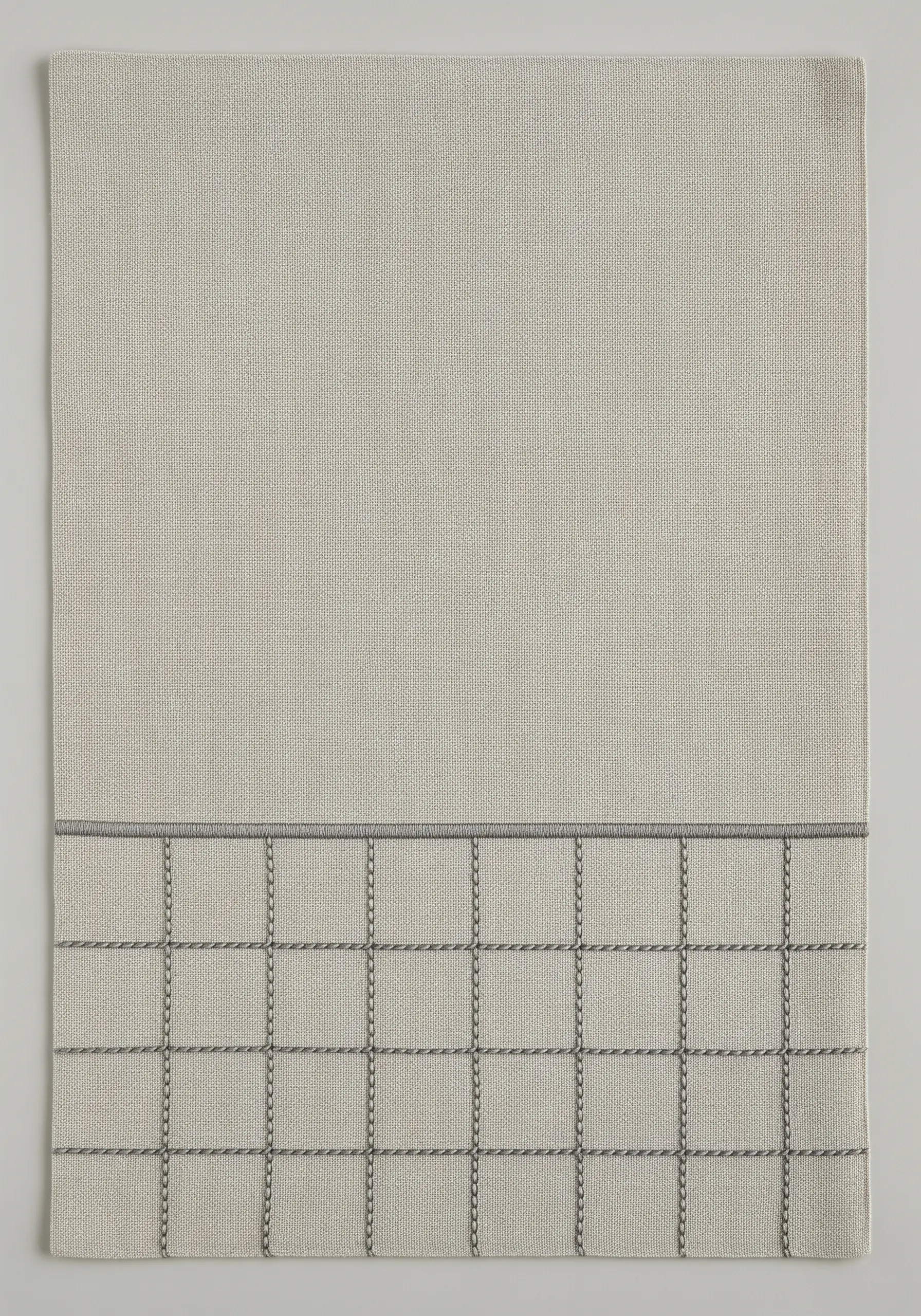 A placemat with a grid pattern embroidered with a darker grey thread, whipped for texture.