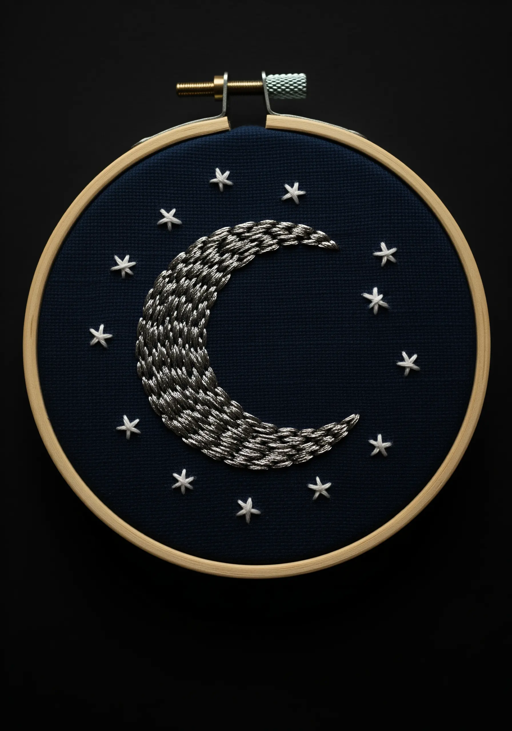 Woven crescent moon using black and silver thread on dark navy fabric.