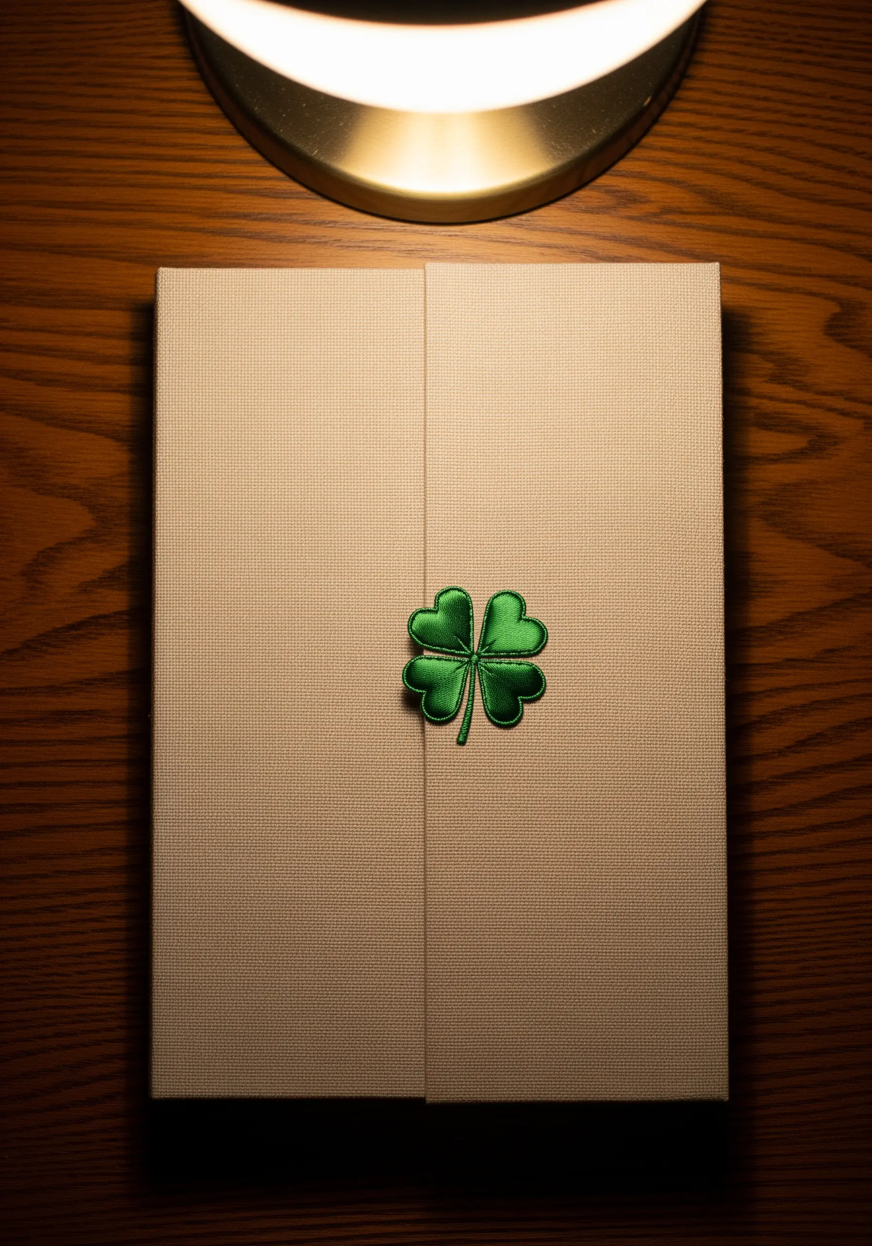A four-leaf clover with outlined petals embroidered on a textured gift box.
