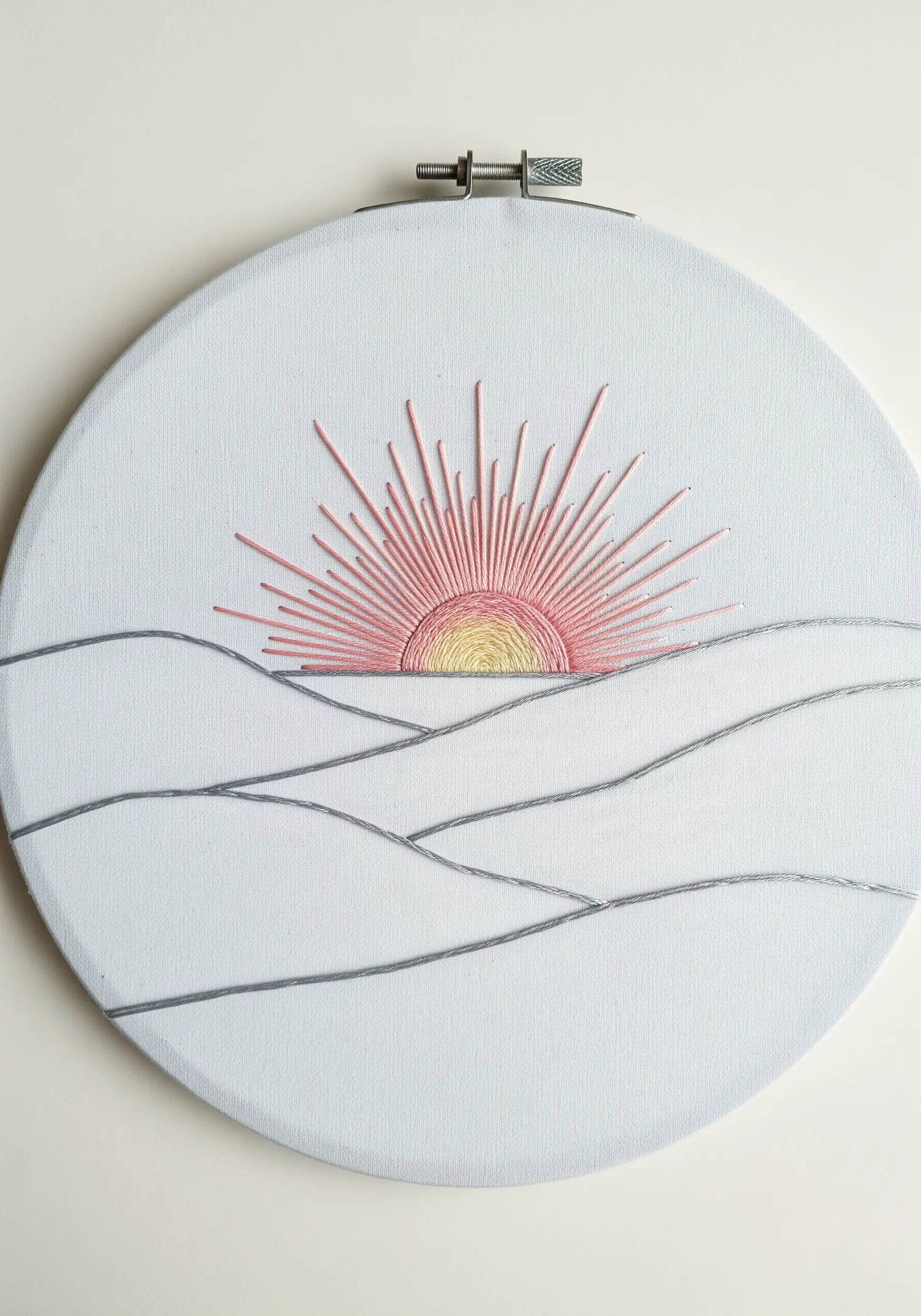 Minimalist sunrise embroidery with radiating straight stitches for sun rays and backstitch hills.
