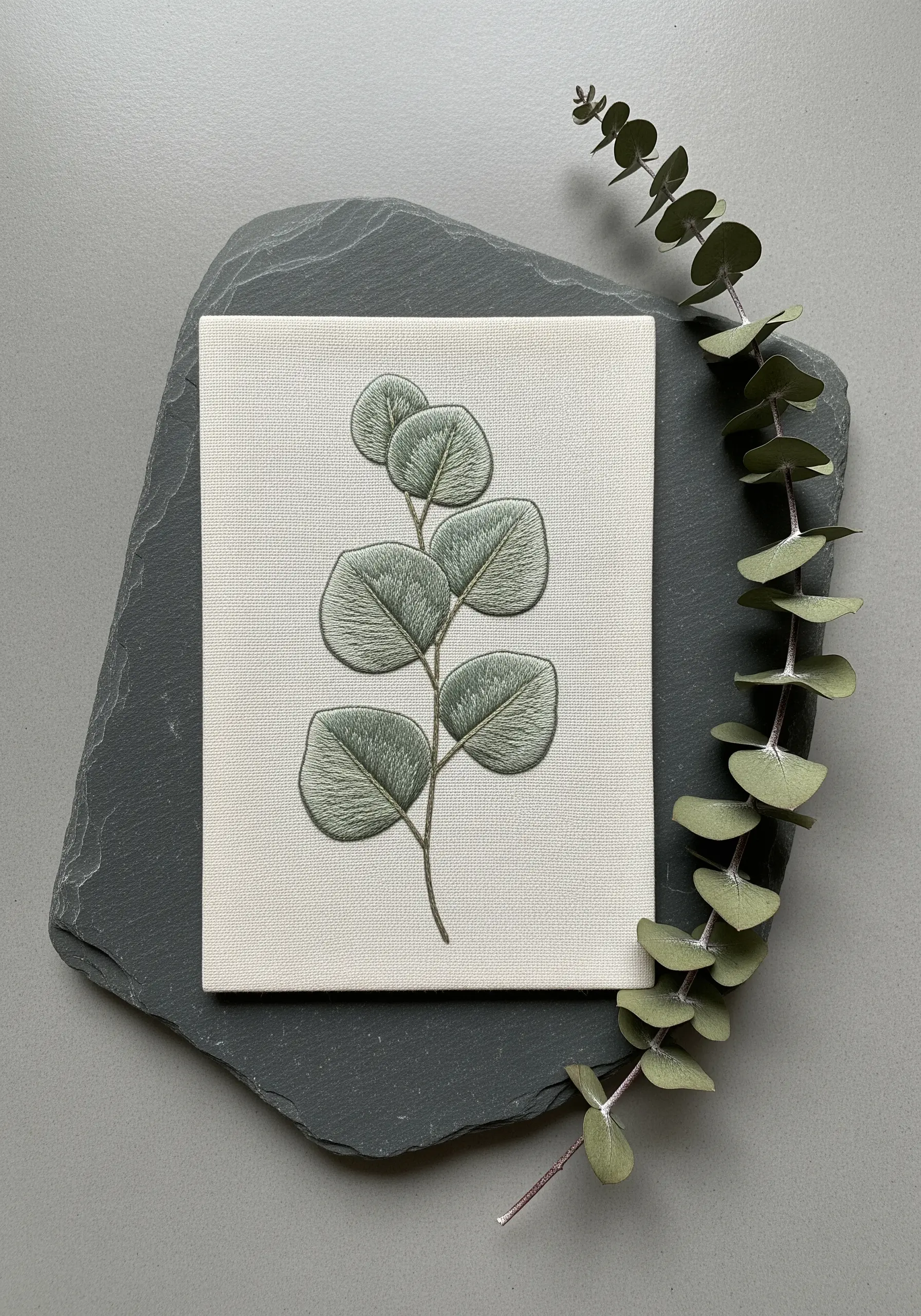 Softly stitched eucalyptus leaves with delicate outlines on a stretched canvas.