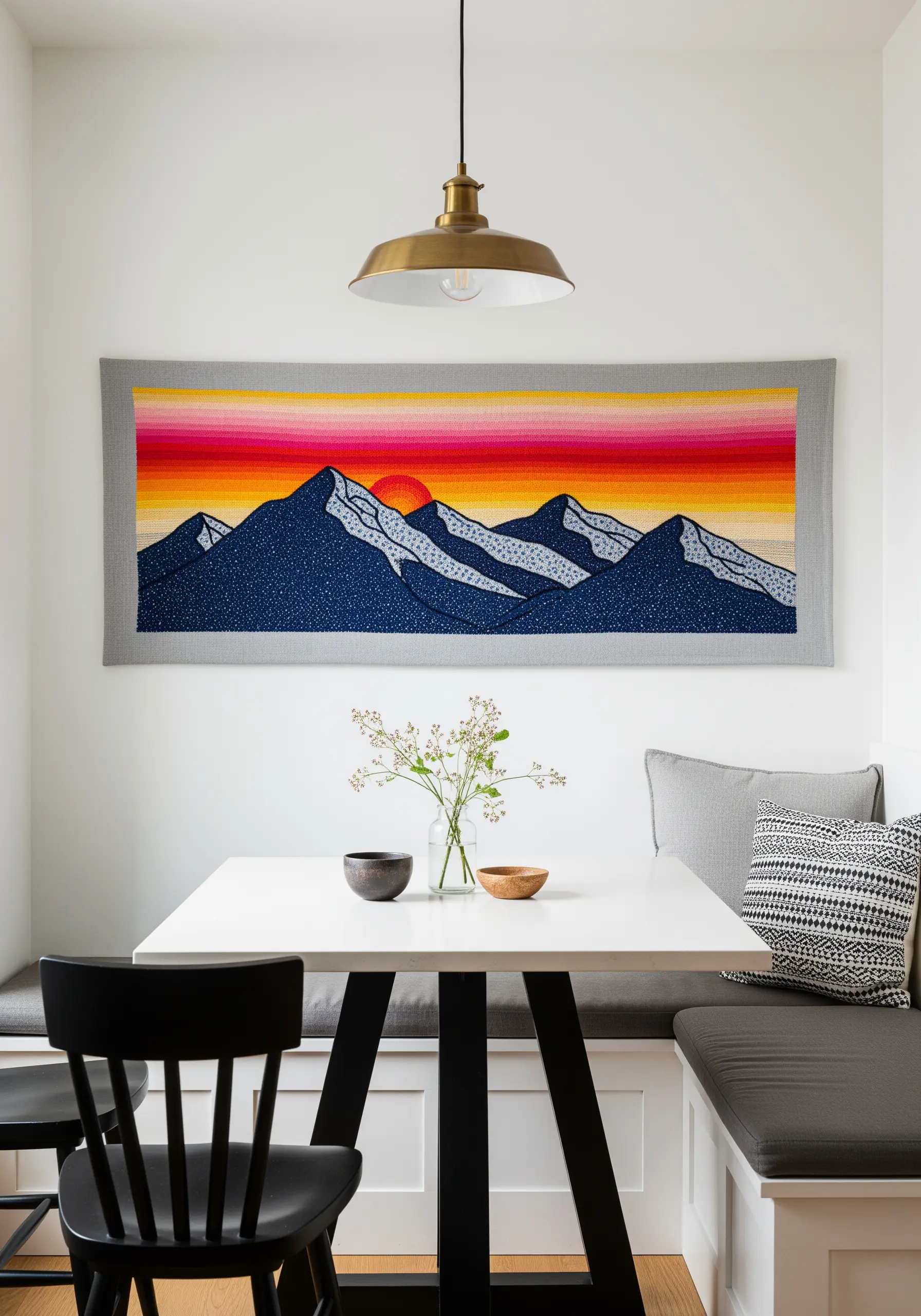A wide embroidered tapestry of a mountain range against a vibrant, color-blocked sunset.