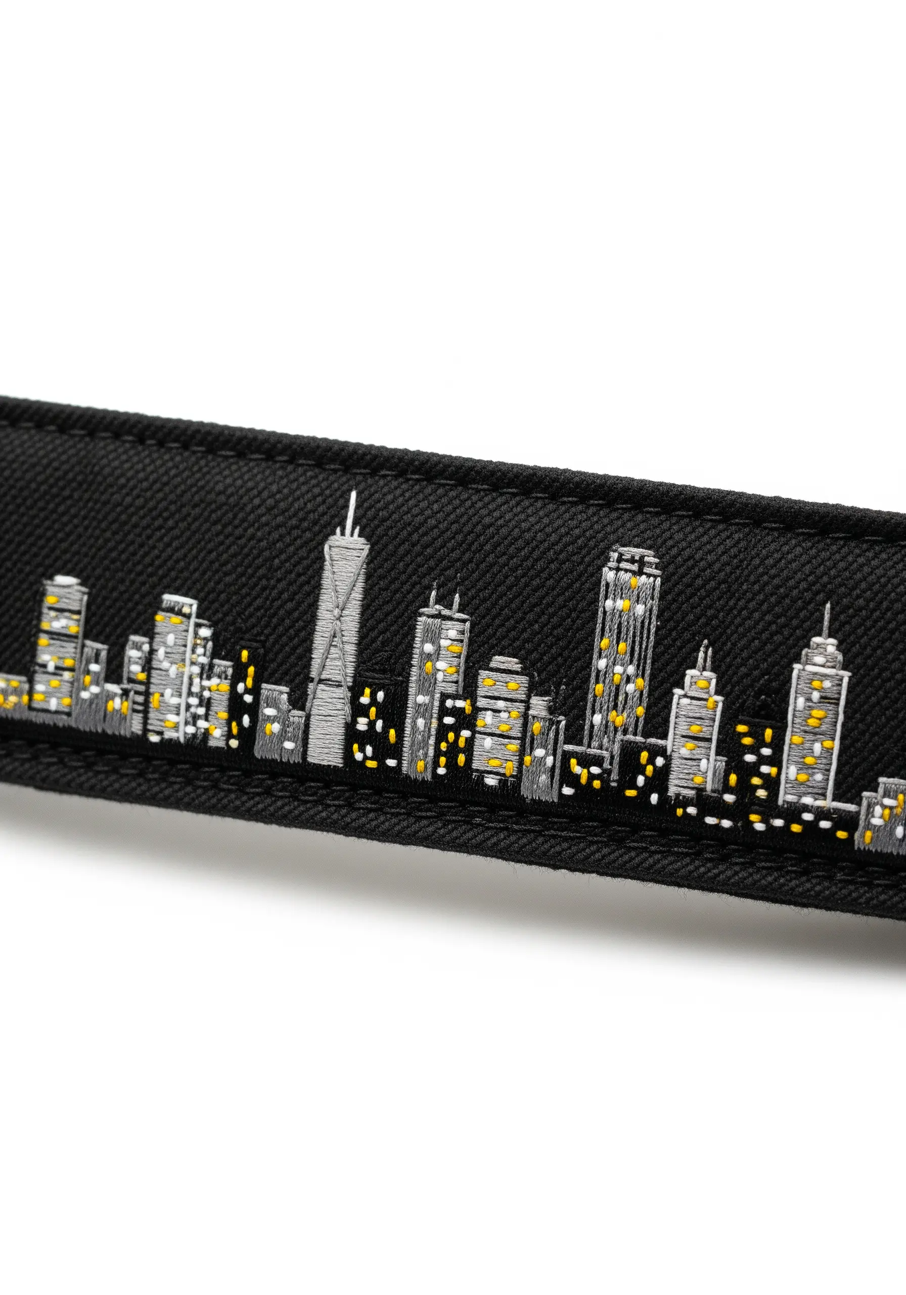 Embroidered cityscape on a black fabric strap with yellow window lights.