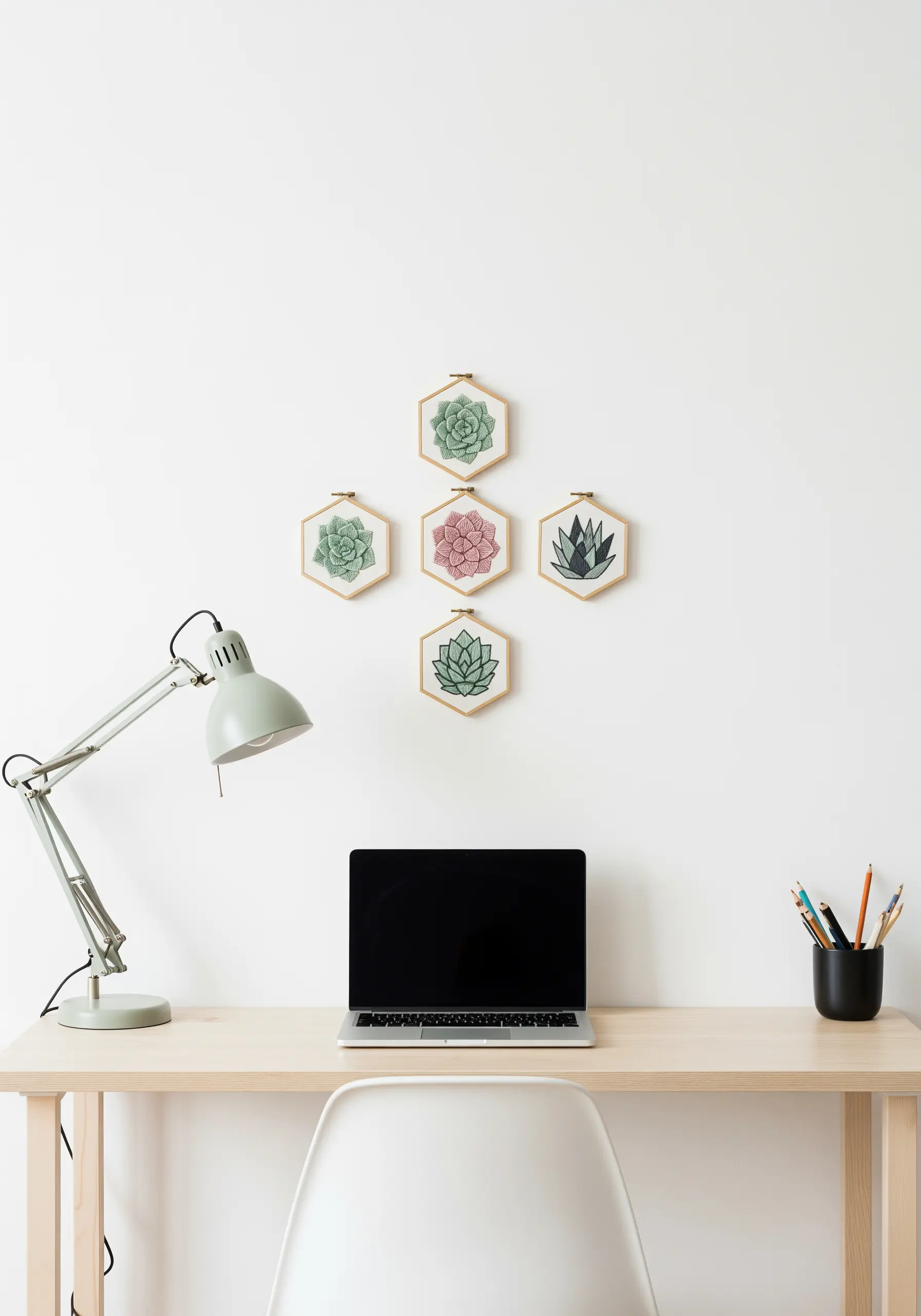 Five hexagonal embroidery hoops with succulent designs in a diamond pattern on a white wall.