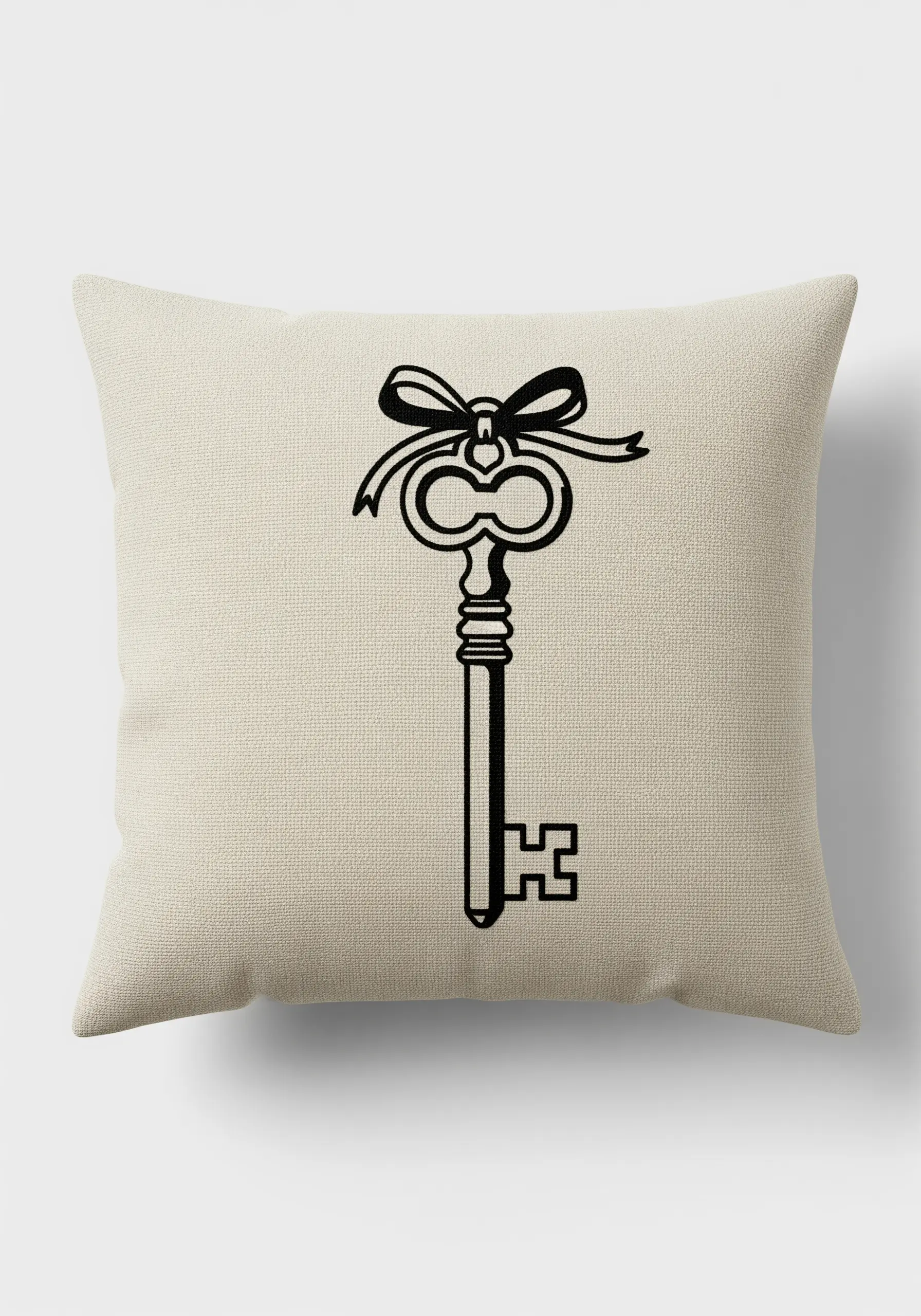 A vintage-style key with a ribbon, embroidered in bold black line art on a cream cushion.