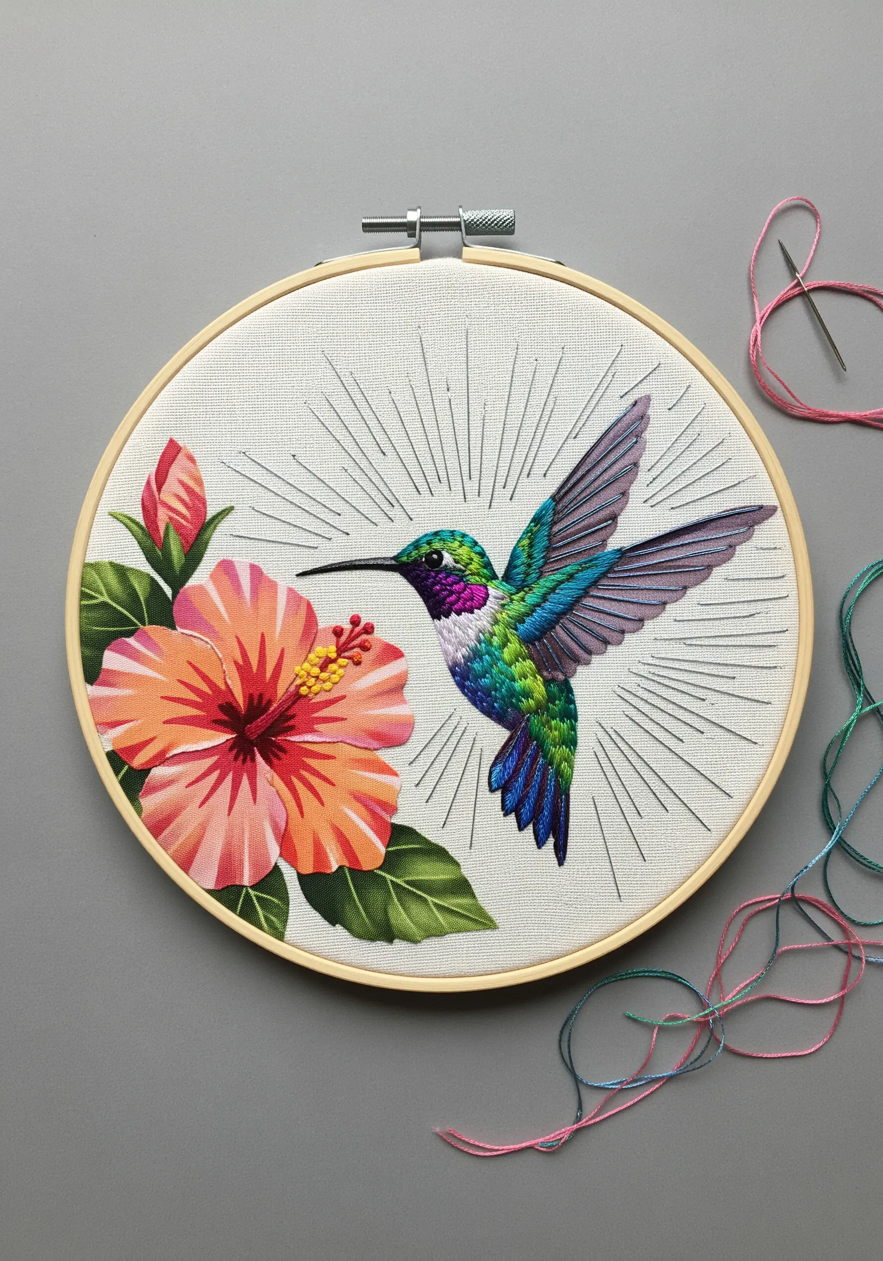 A detailed thread-painted hummingbird with blended green, blue, and purple feathers.