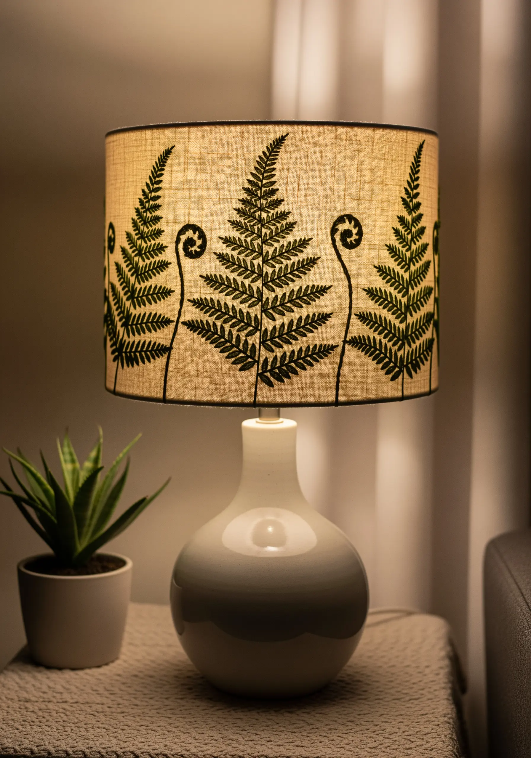 Dark green fern silhouettes embroidered around a textured linen lampshade.