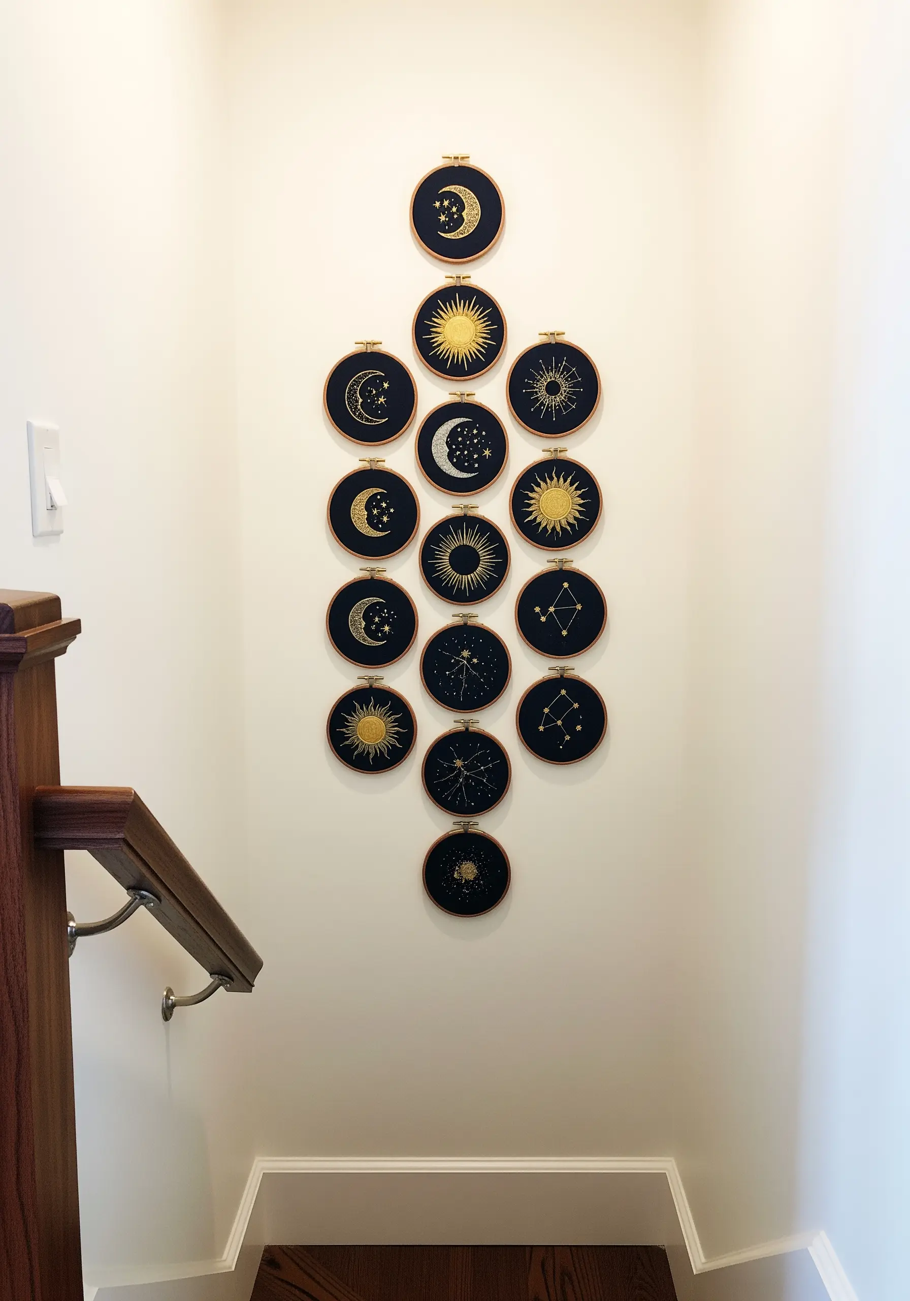 A large collection of celestial-themed embroidery hoops with gold thread on navy fabric.
