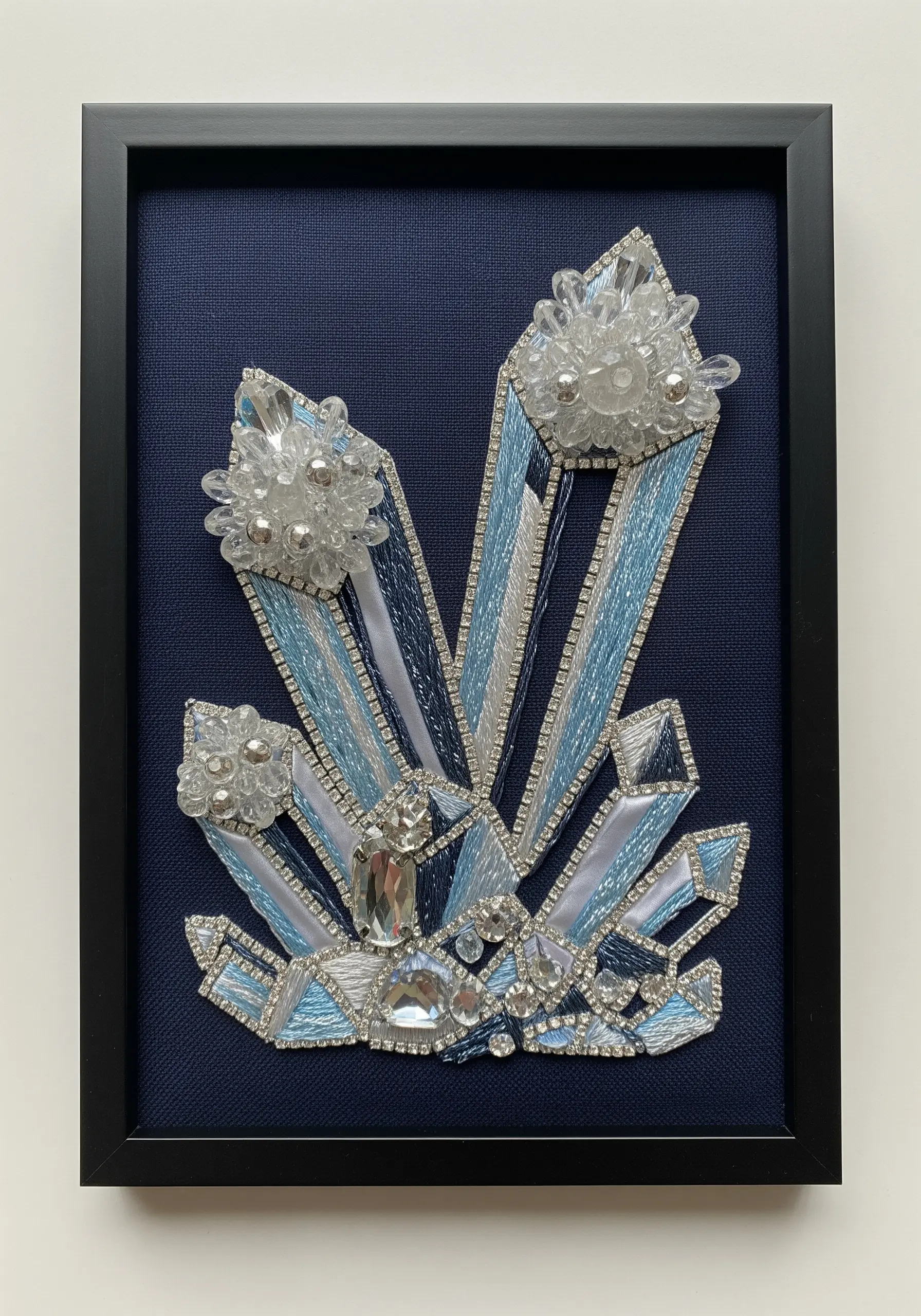 A framed mixed-media embroidery of blue and white crystal clusters using beads, rhinestones, and thread.