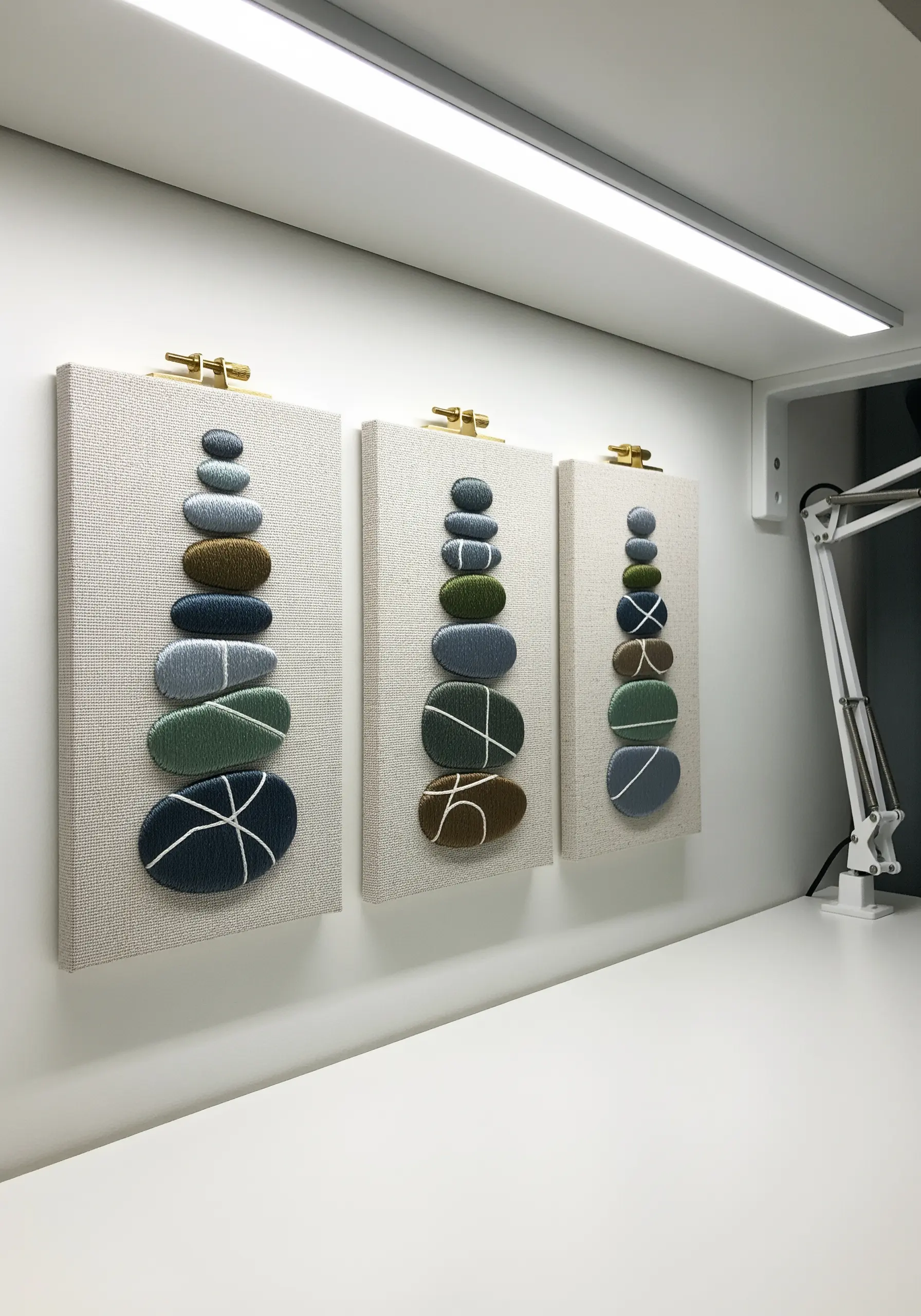 A triptych of embroidered stacked stones, with each stone having a raised, 3D effect.