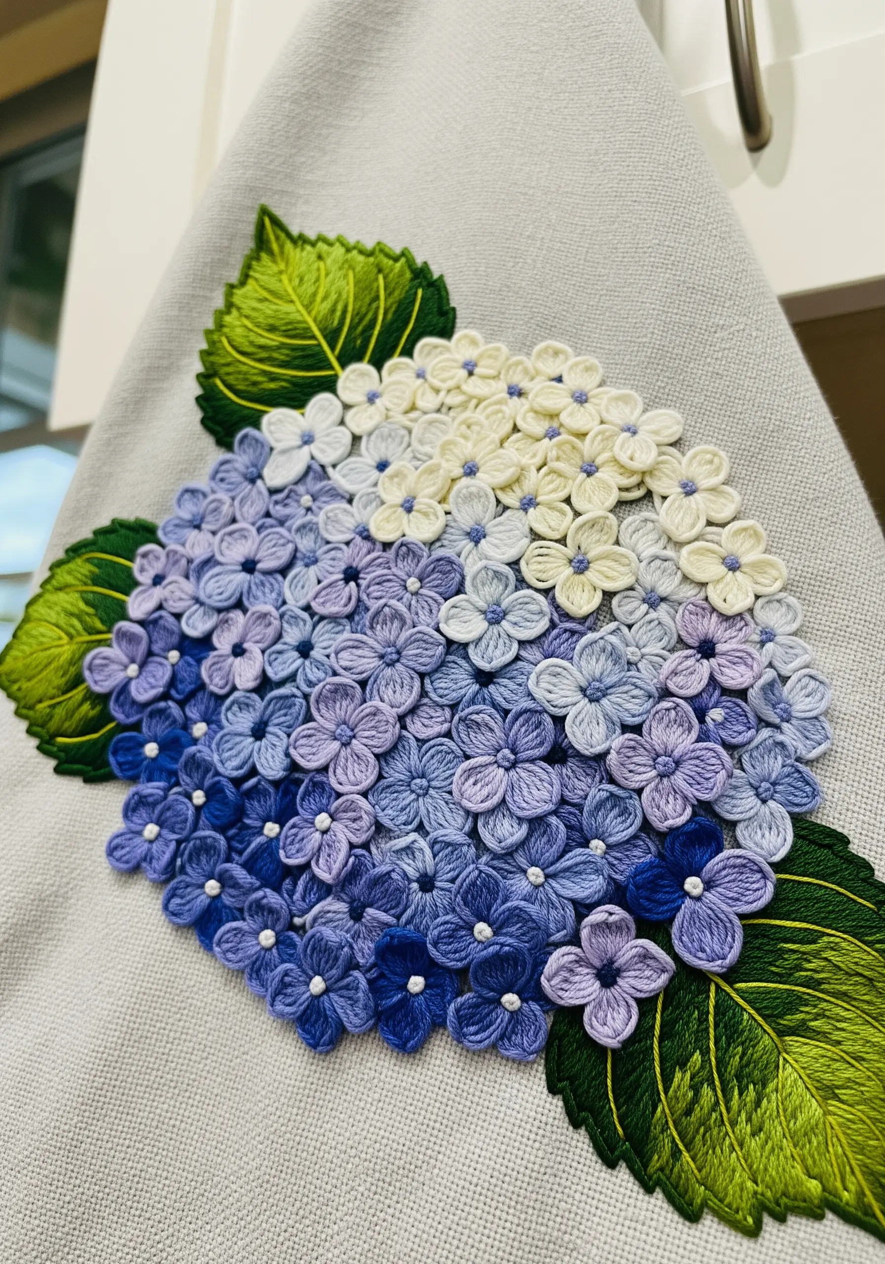 A dense cluster of embroidered hydrangea flowers in shades of purple, blue, and white.