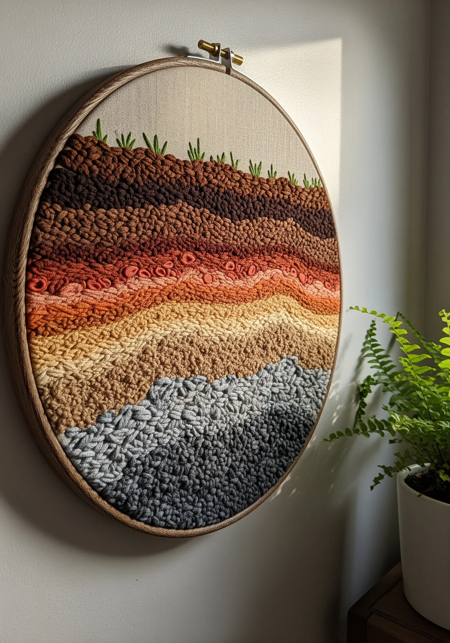 Hoop art showing textured soil layers in browns and reds using various stitches.