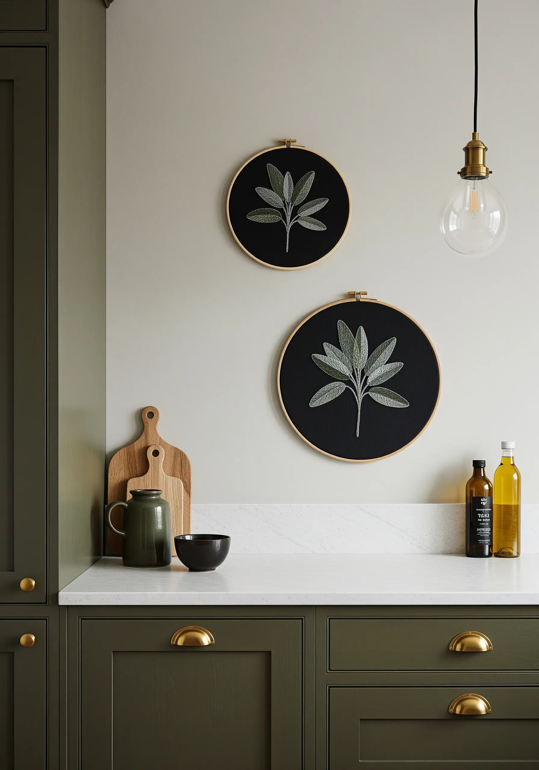 Two hoops with sage branches embroidered in soft greens and grays on black fabric.