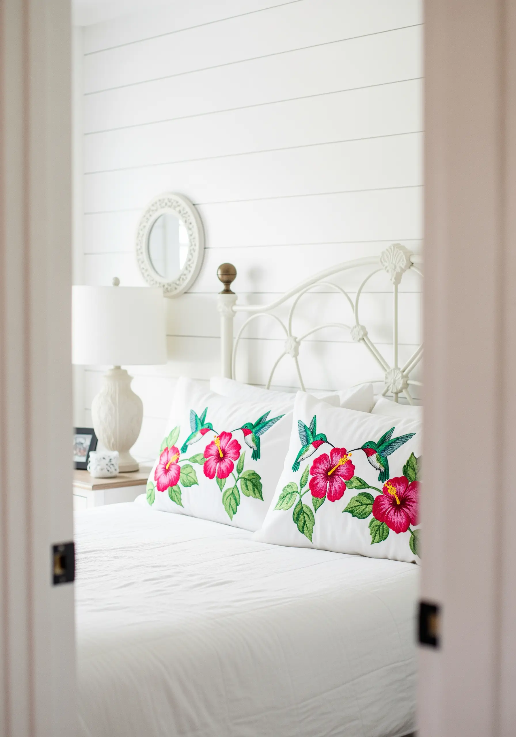 Embroidered pillows featuring vibrant hummingbirds and pink hibiscus flowers.