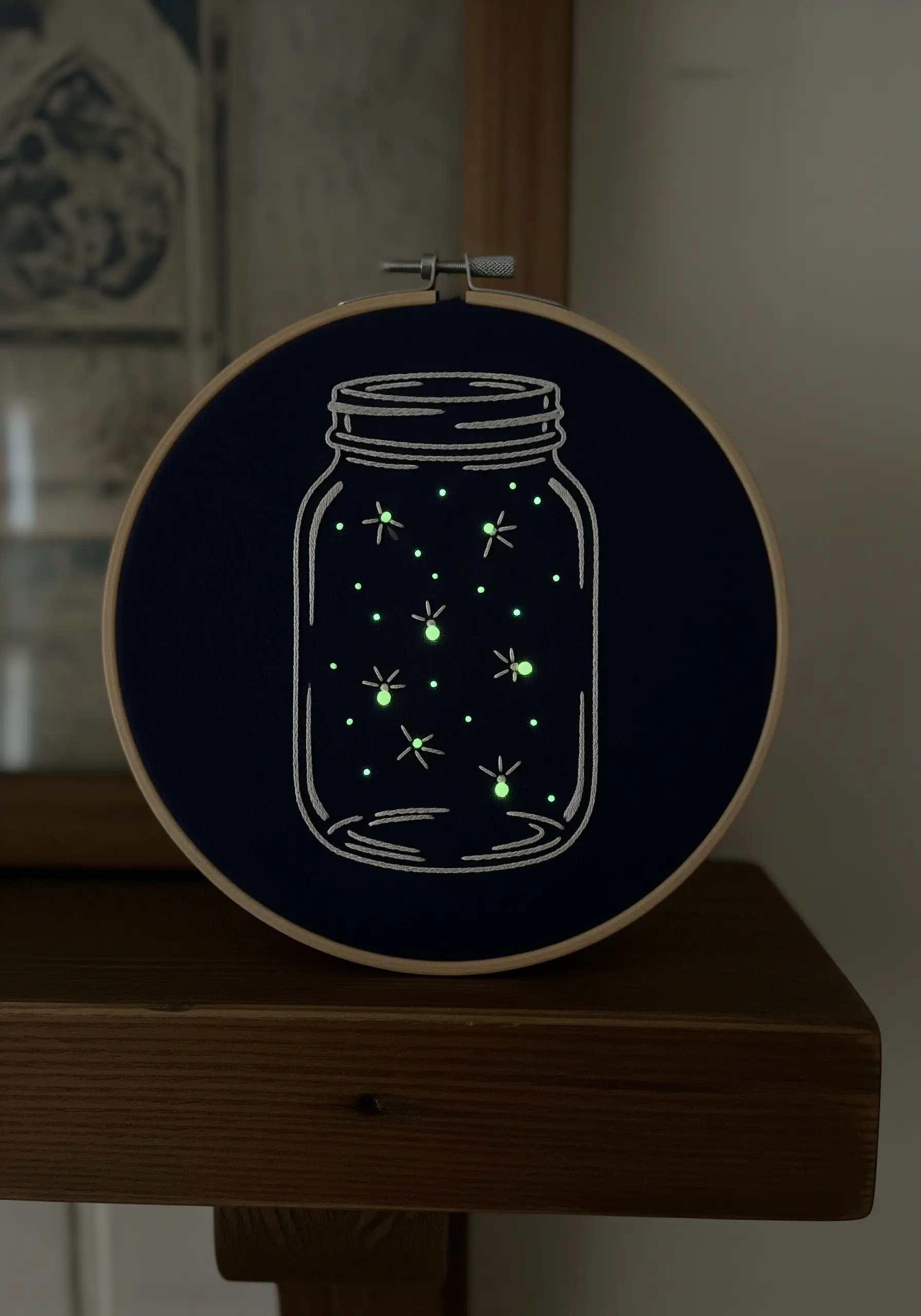 Embroidery of fireflies in a jar, with the fireflies stitched in glow-in-the-dark thread.