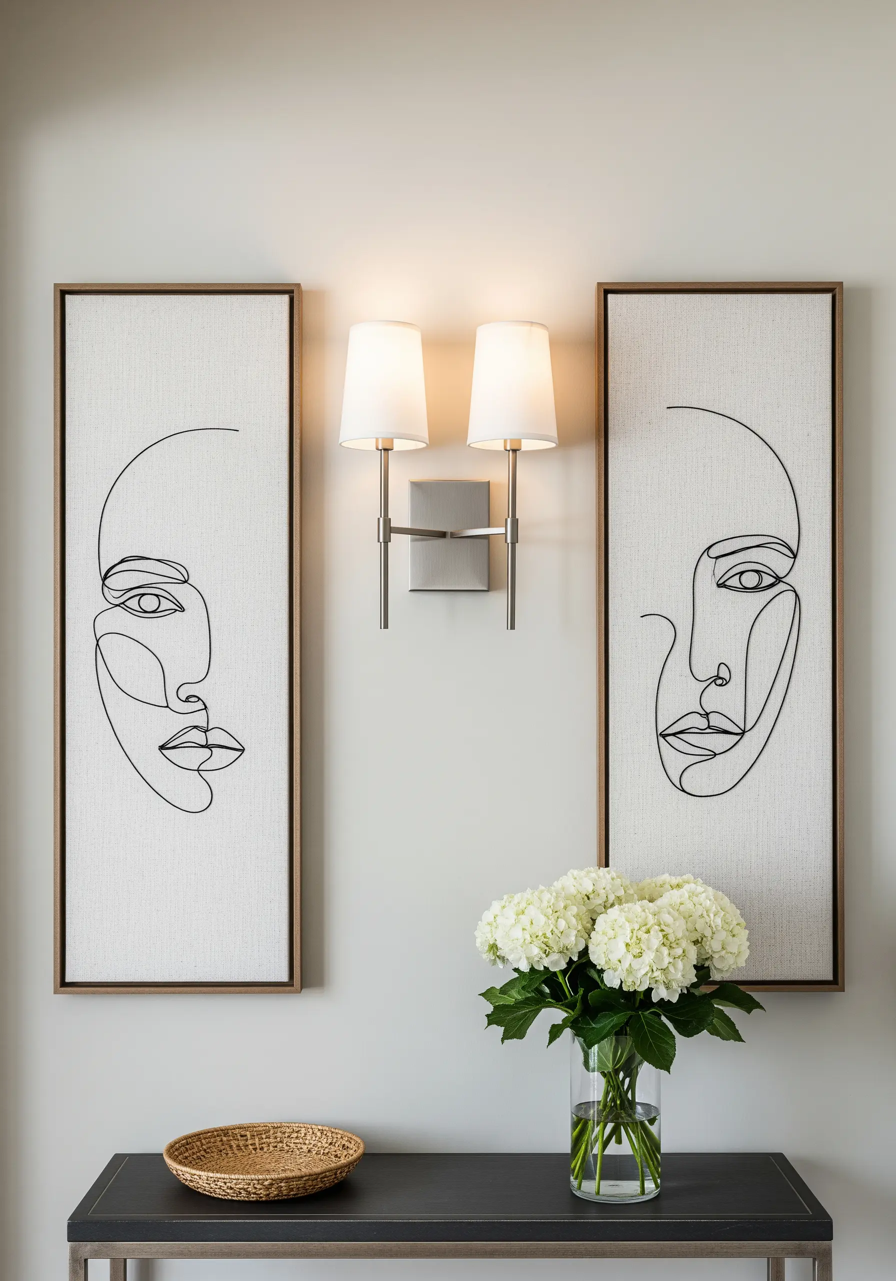 Two tall frames with minimalist, single-line abstract face drawings in black thread.
