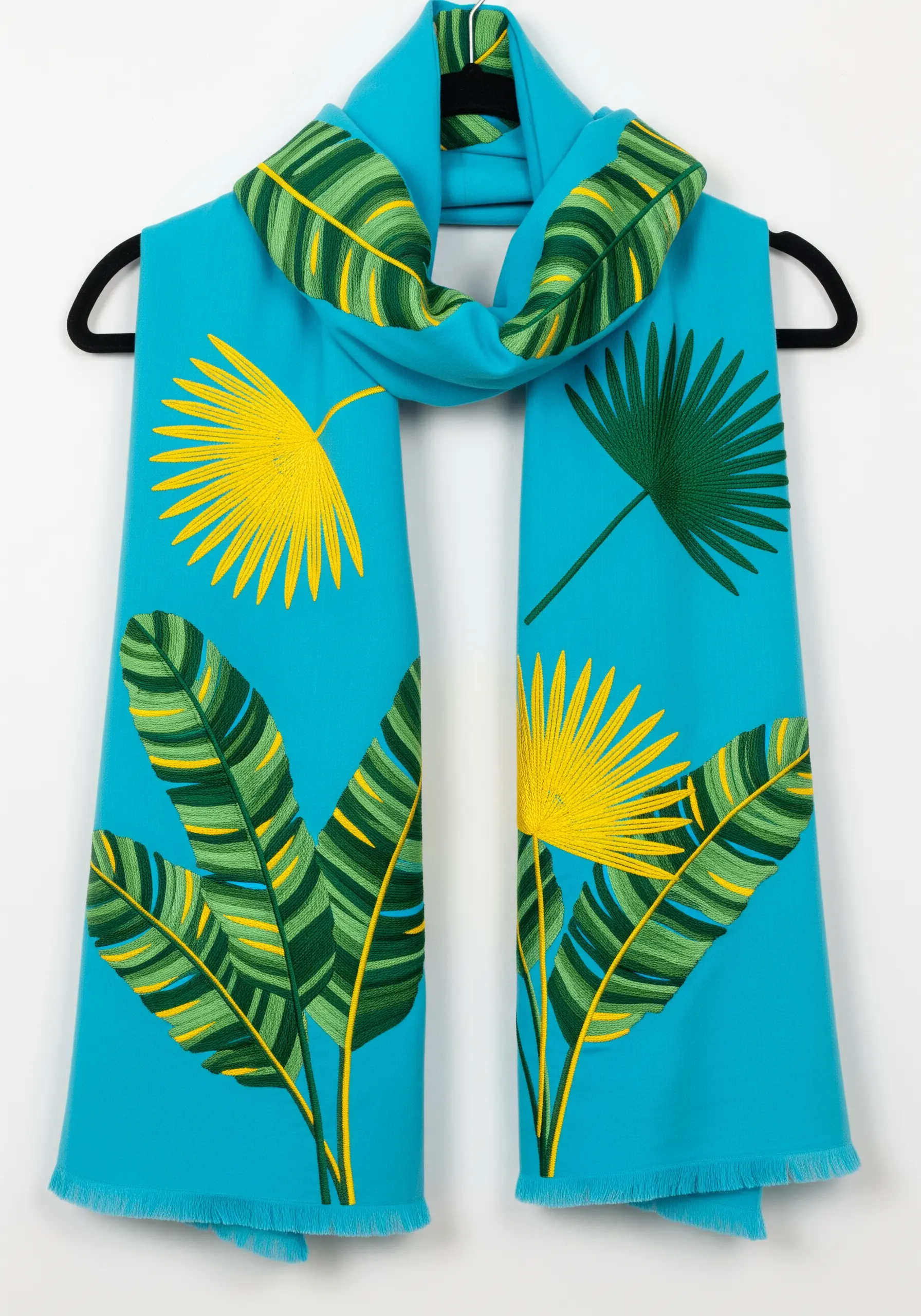 Graphic, color-blocked tropical leaves in green and yellow on a bright blue scarf.