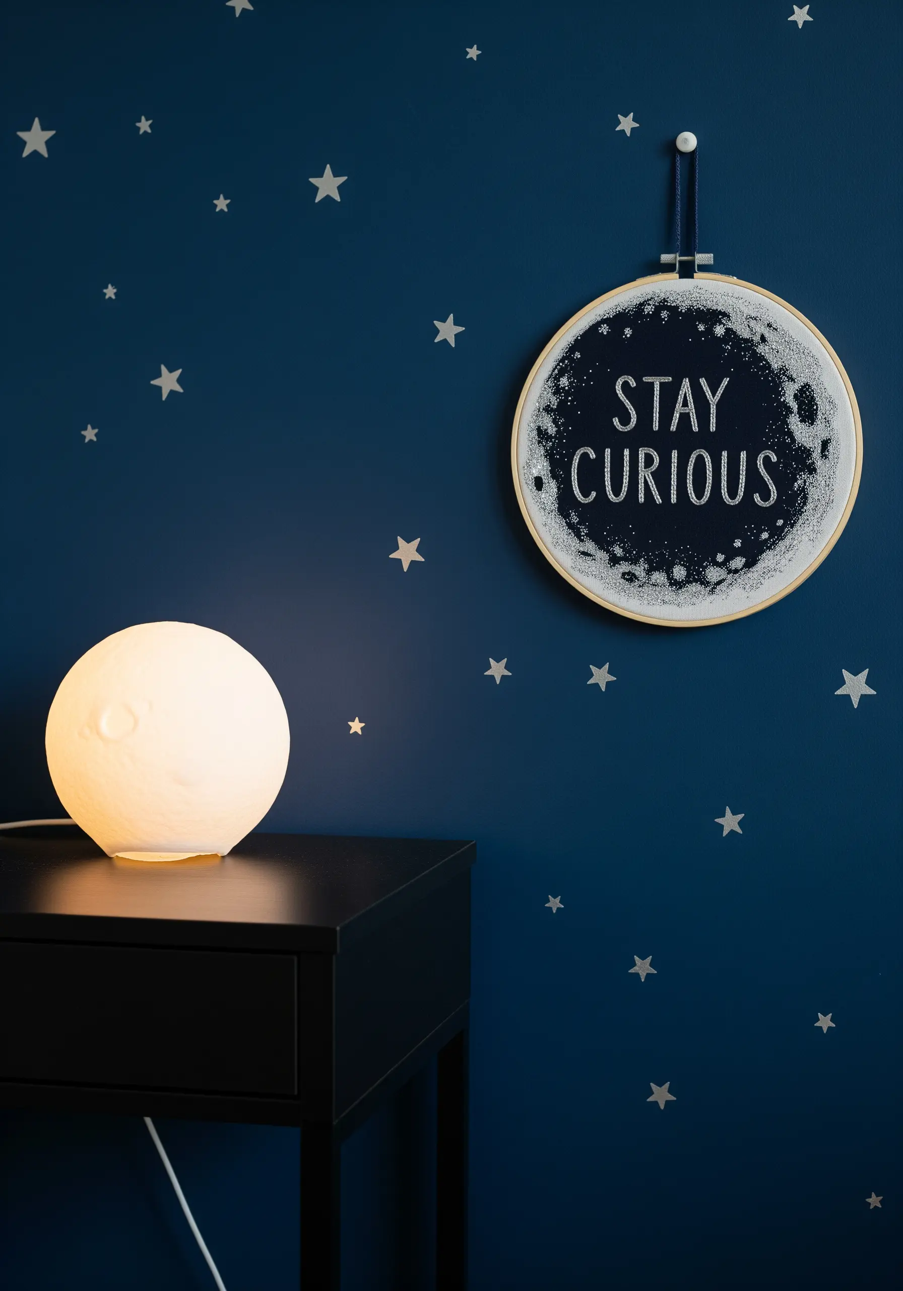A 'Stay Curious' quote embroidered on a background of French knot stars in a hoop.