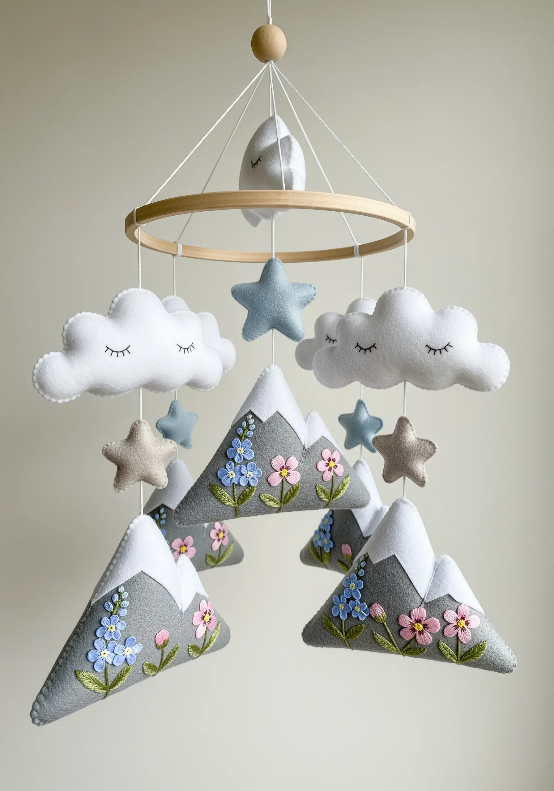 A nursery mobile made of felt mountains, clouds, and stars, embellished with simple floral embroidery