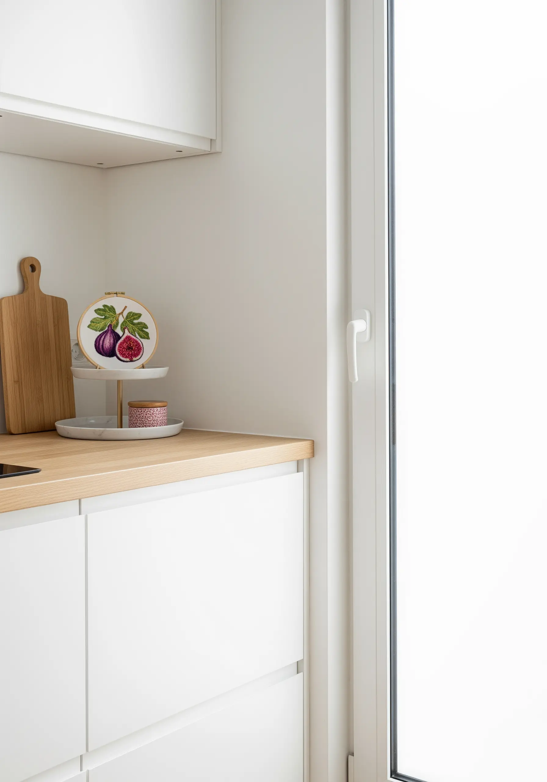 A detailed embroidery of sliced figs, displayed on a tiered tray in a bright white kitchen.