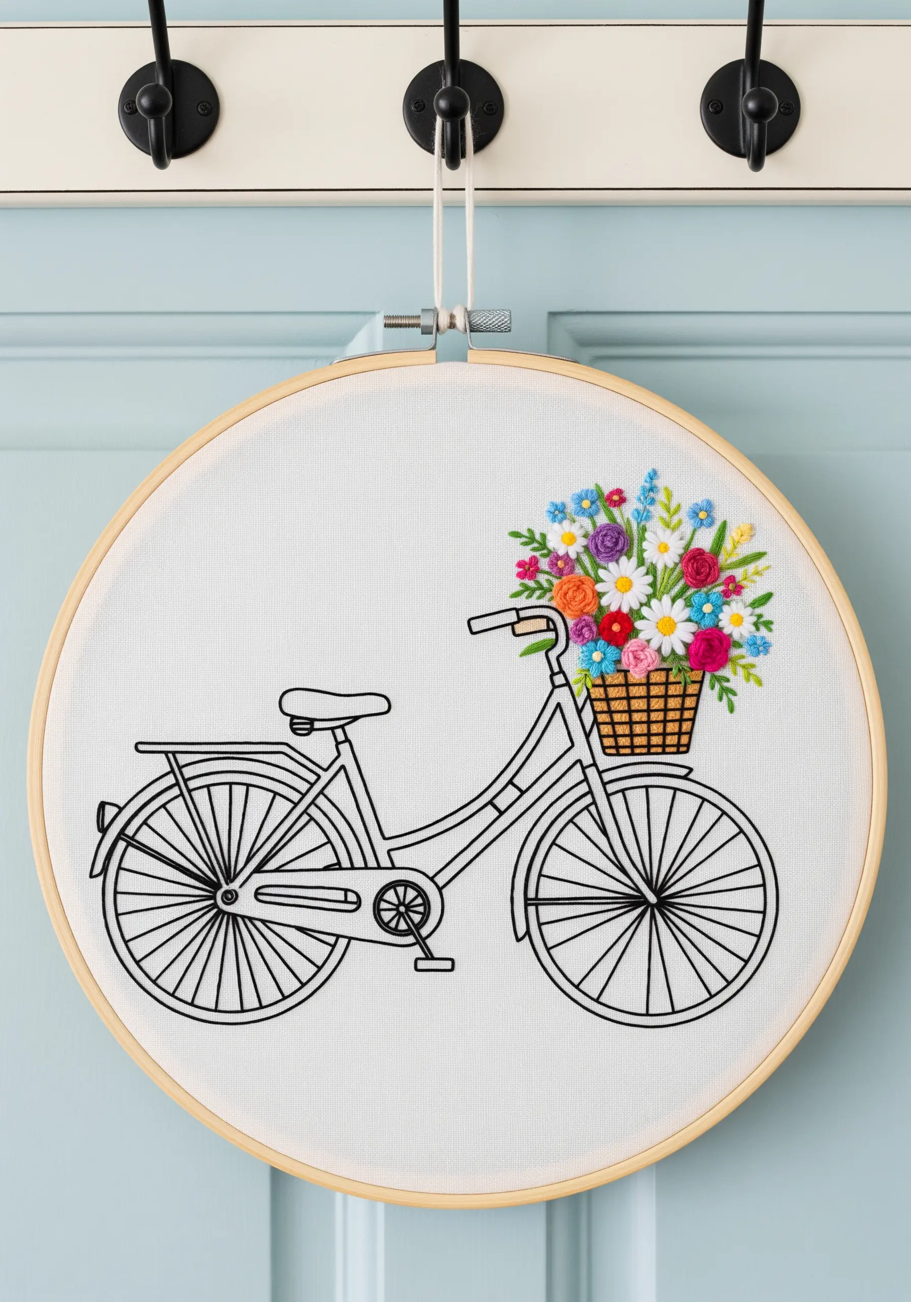 A line art embroidery of a bicycle with a basket overflowing with colorful, textured flowers.