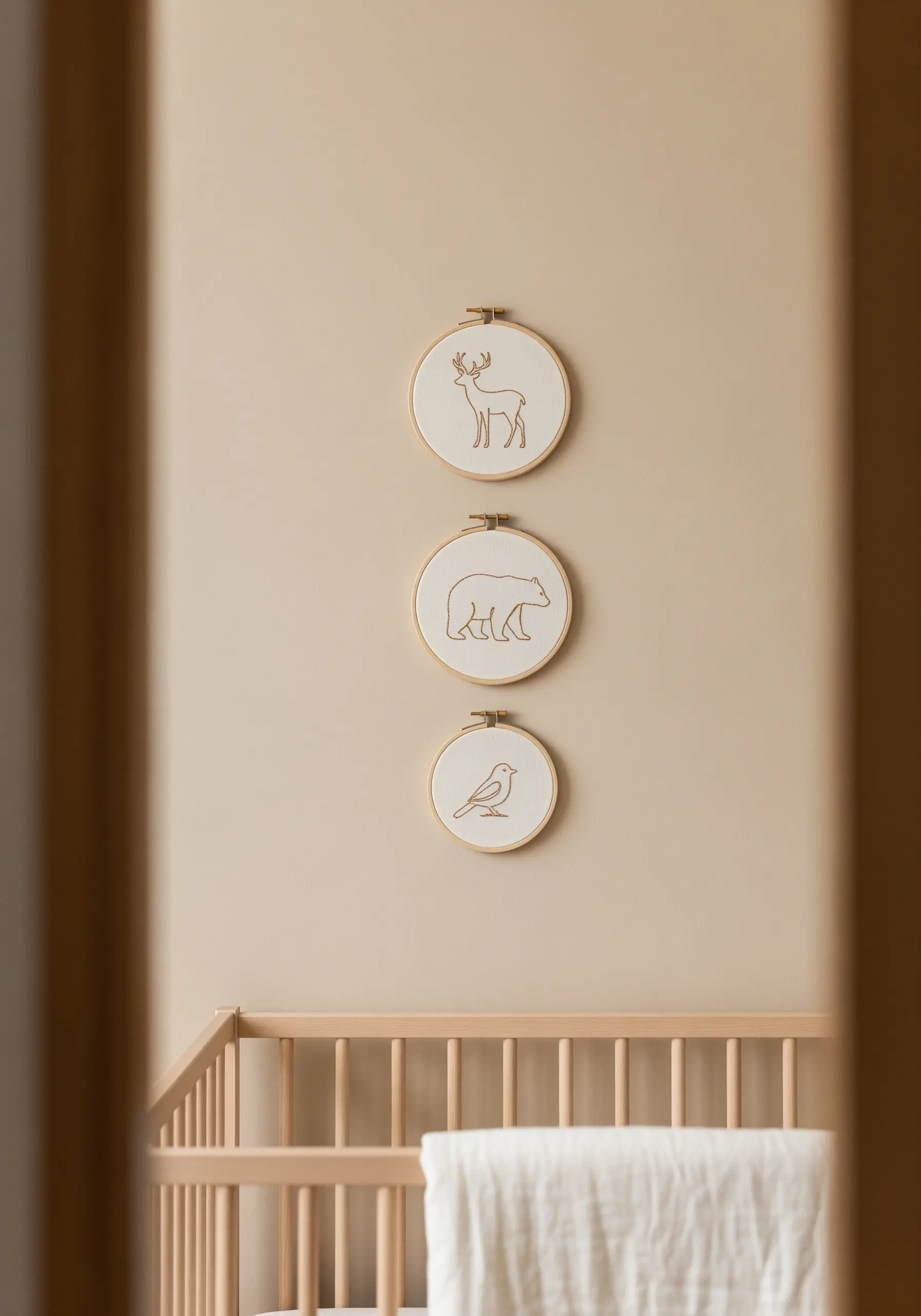 Three small embroidery hoops with minimalist line art of a deer, bear, and bird.