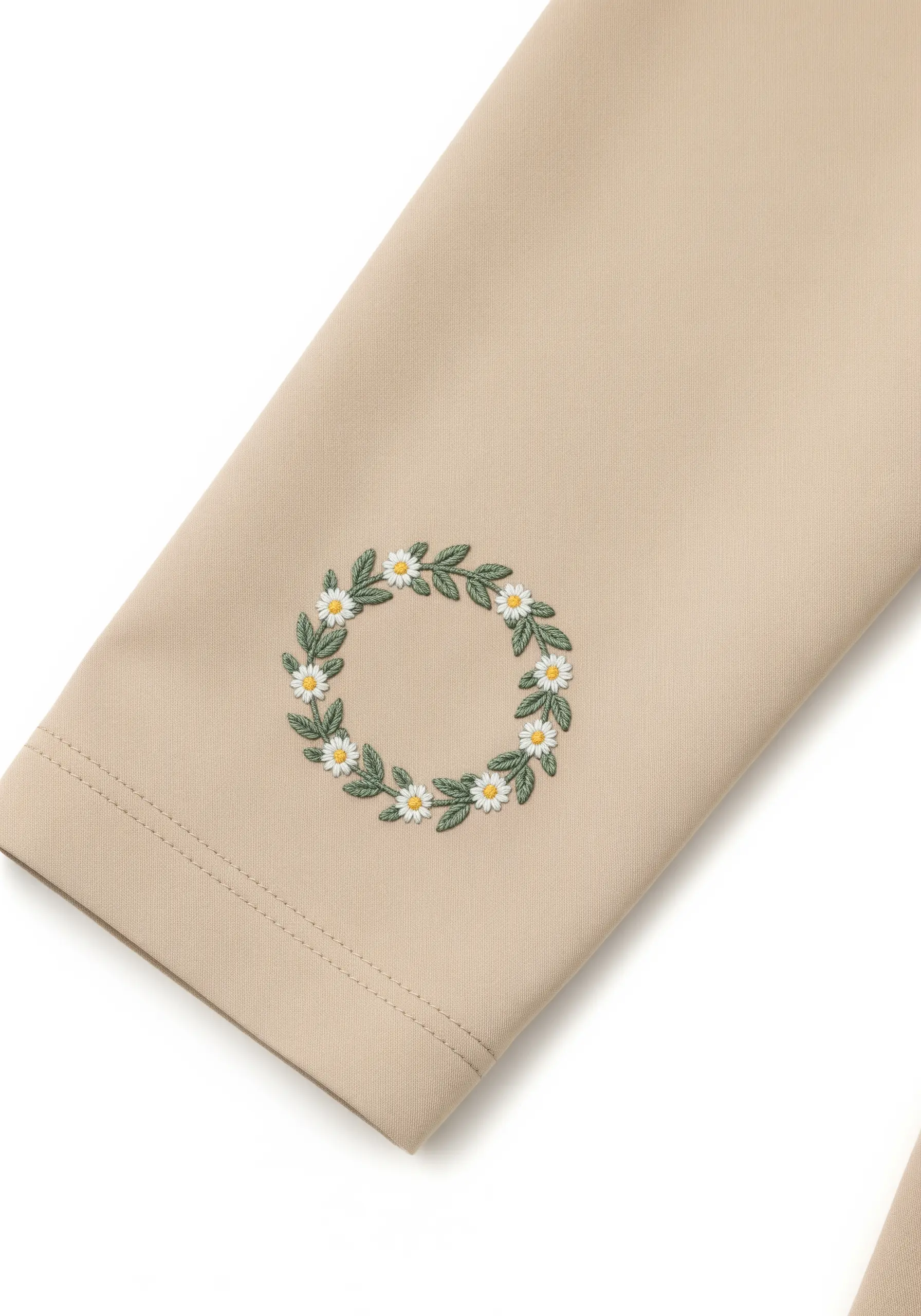 An embroidered wreath of daisies and leaves on the sleeve of a beige jacket.