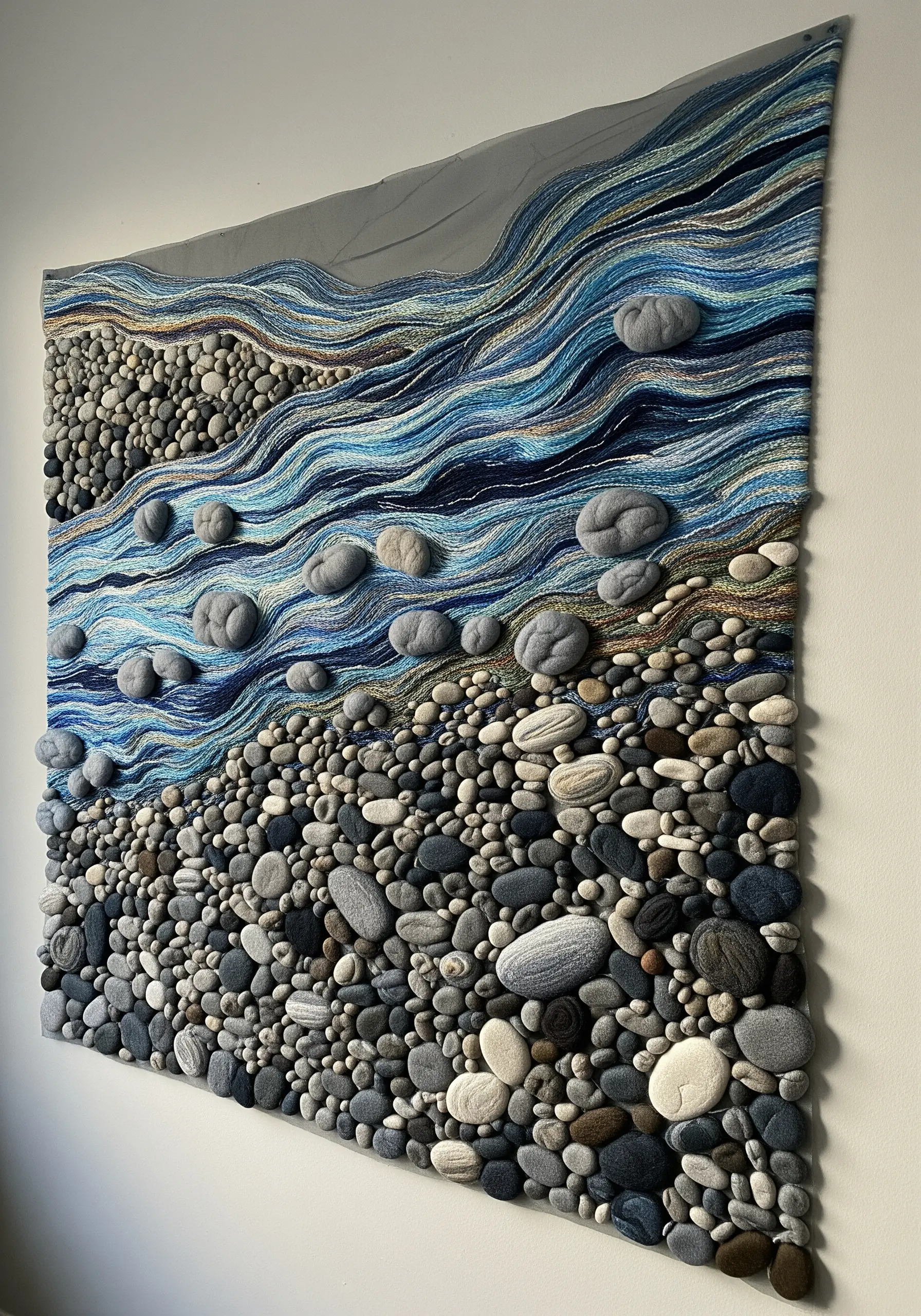 A large textile wall art piece depicting a riverbed with 3D fabric stones and thread-painted water.