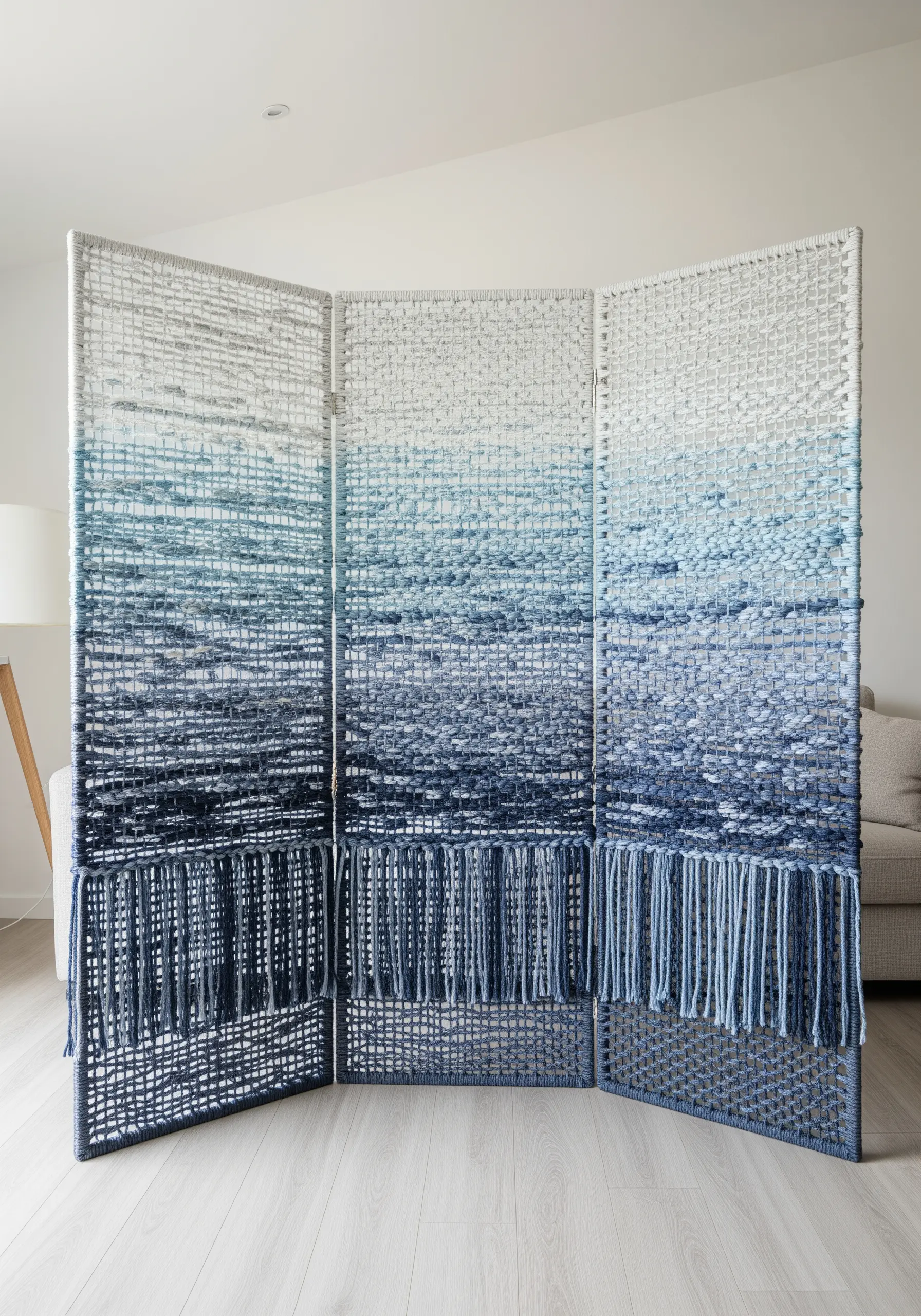 A three-panel room divider woven with a blue-to-white gradient yarn in an open-weave style.