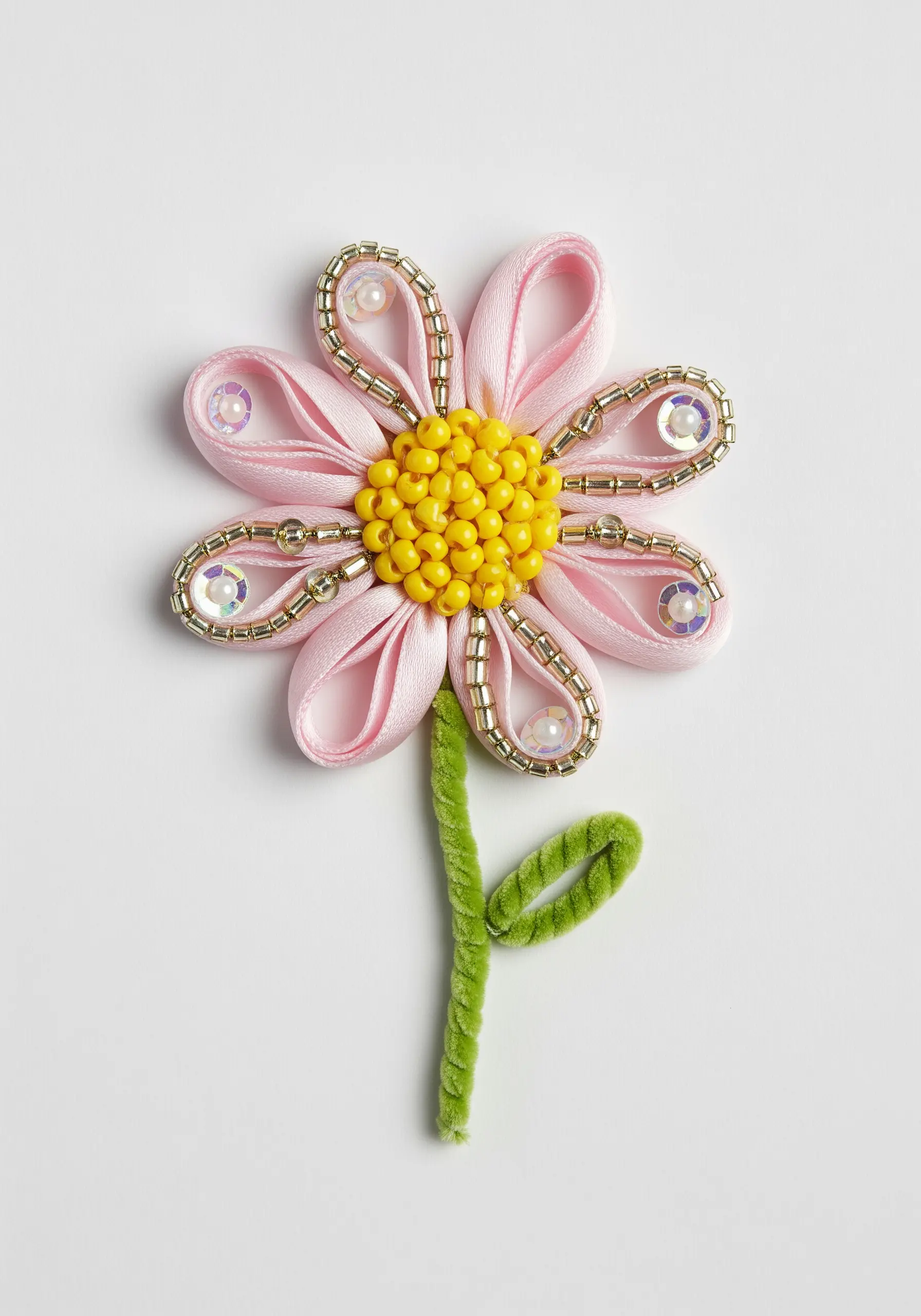 A pink flower made with satin ribbon loops, beads, and a green pipe cleaner stem.
