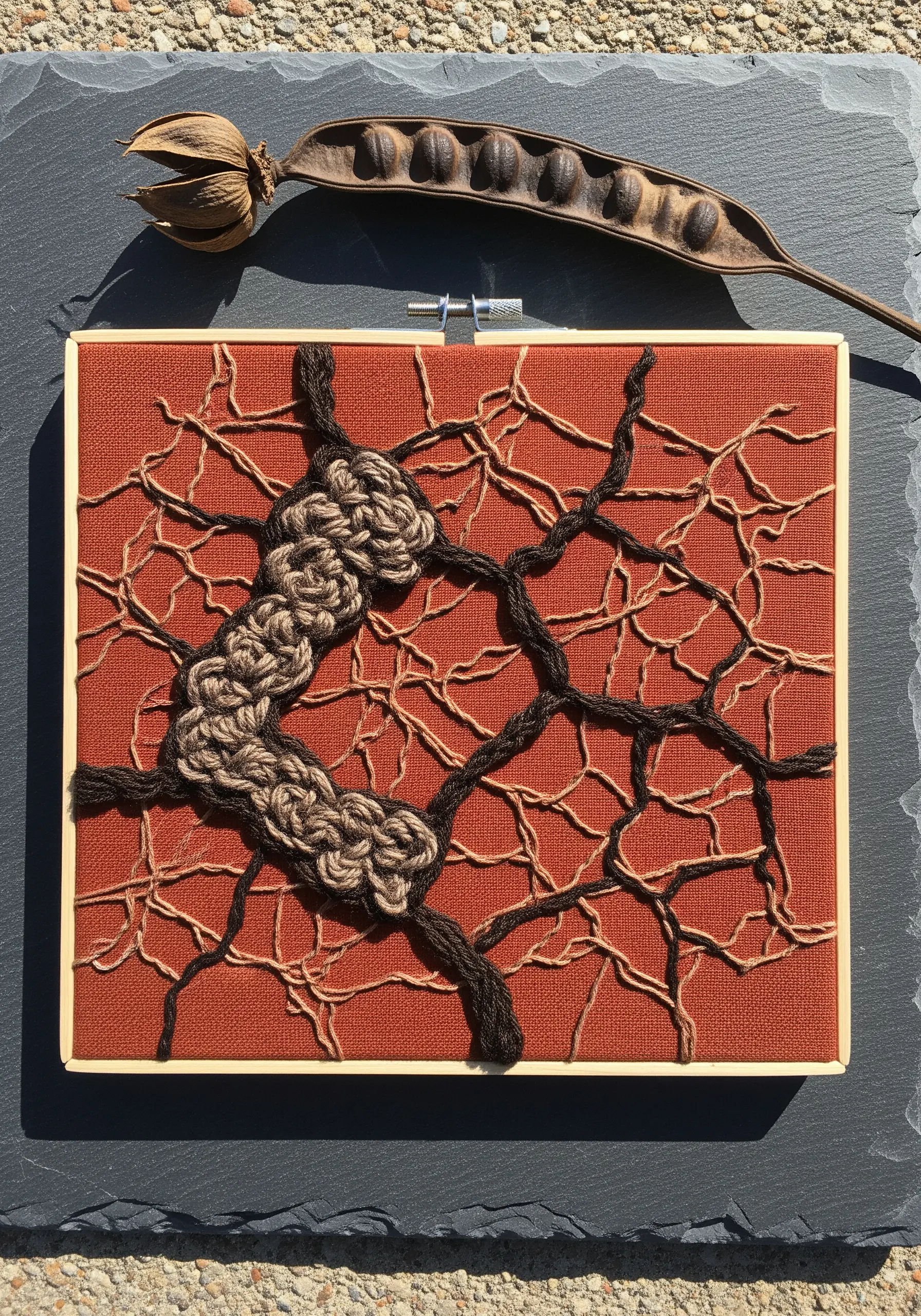 Abstract root system embroidery with thick, couched yarn and thin, delicate stitched lines on red fabric.