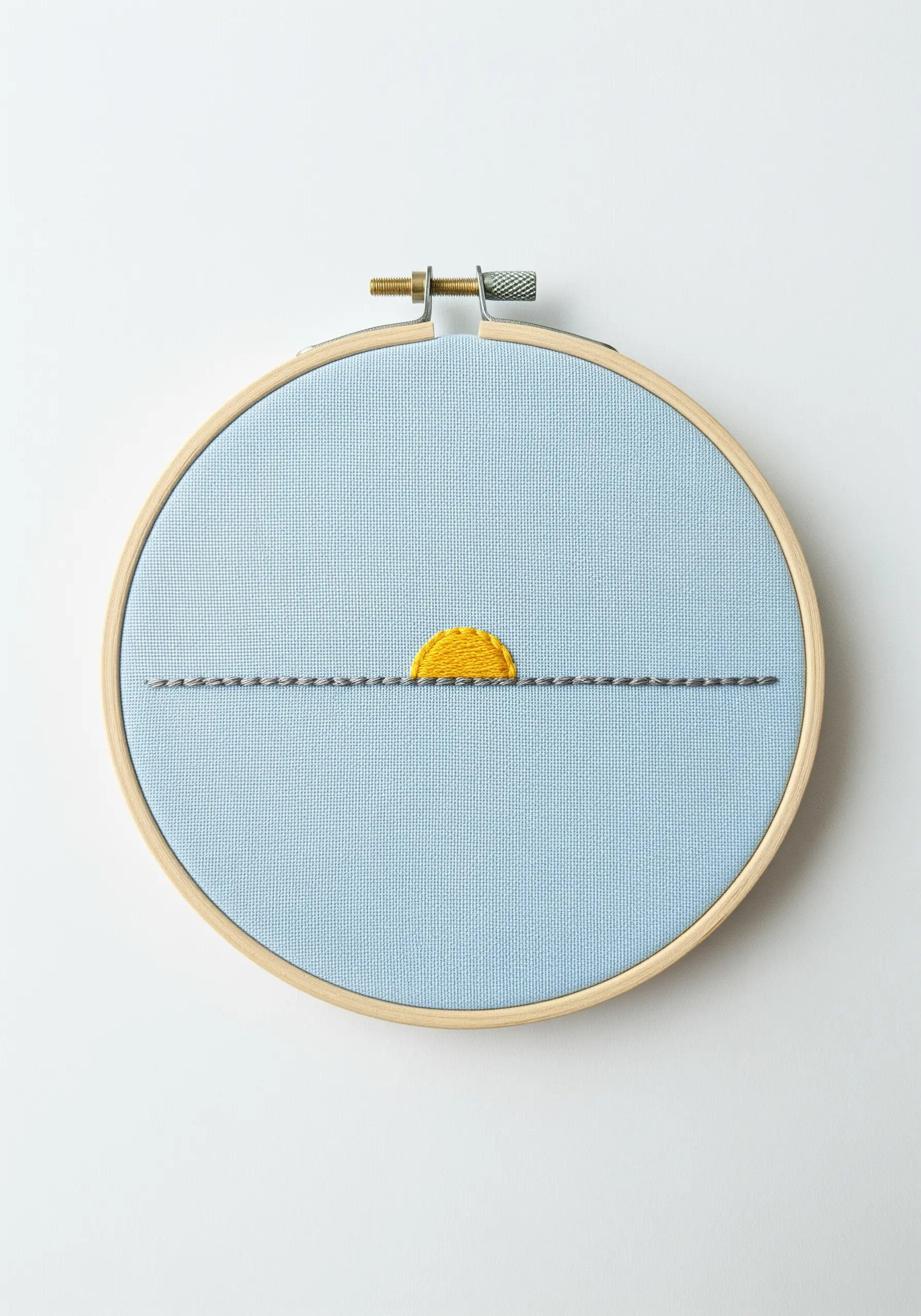 A minimalist sunset with a yellow satin stitch sun and a grey backstitch horizon line.