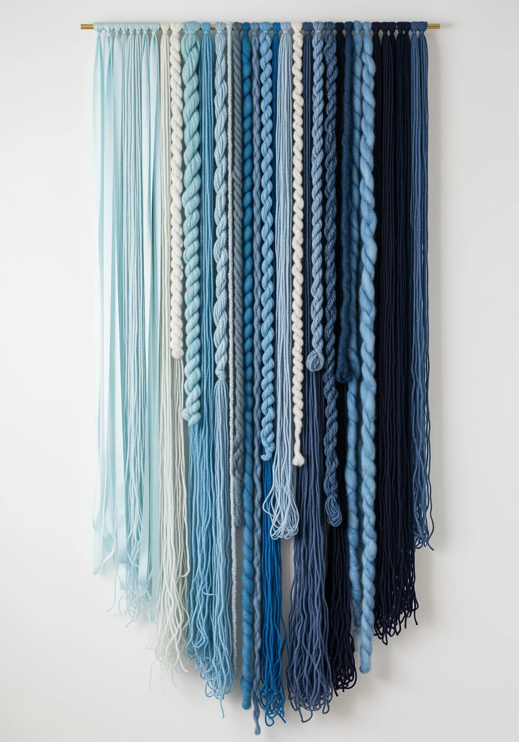 Wall hanging made of various yarns and ribbons arranged in a blue ombré gradient.