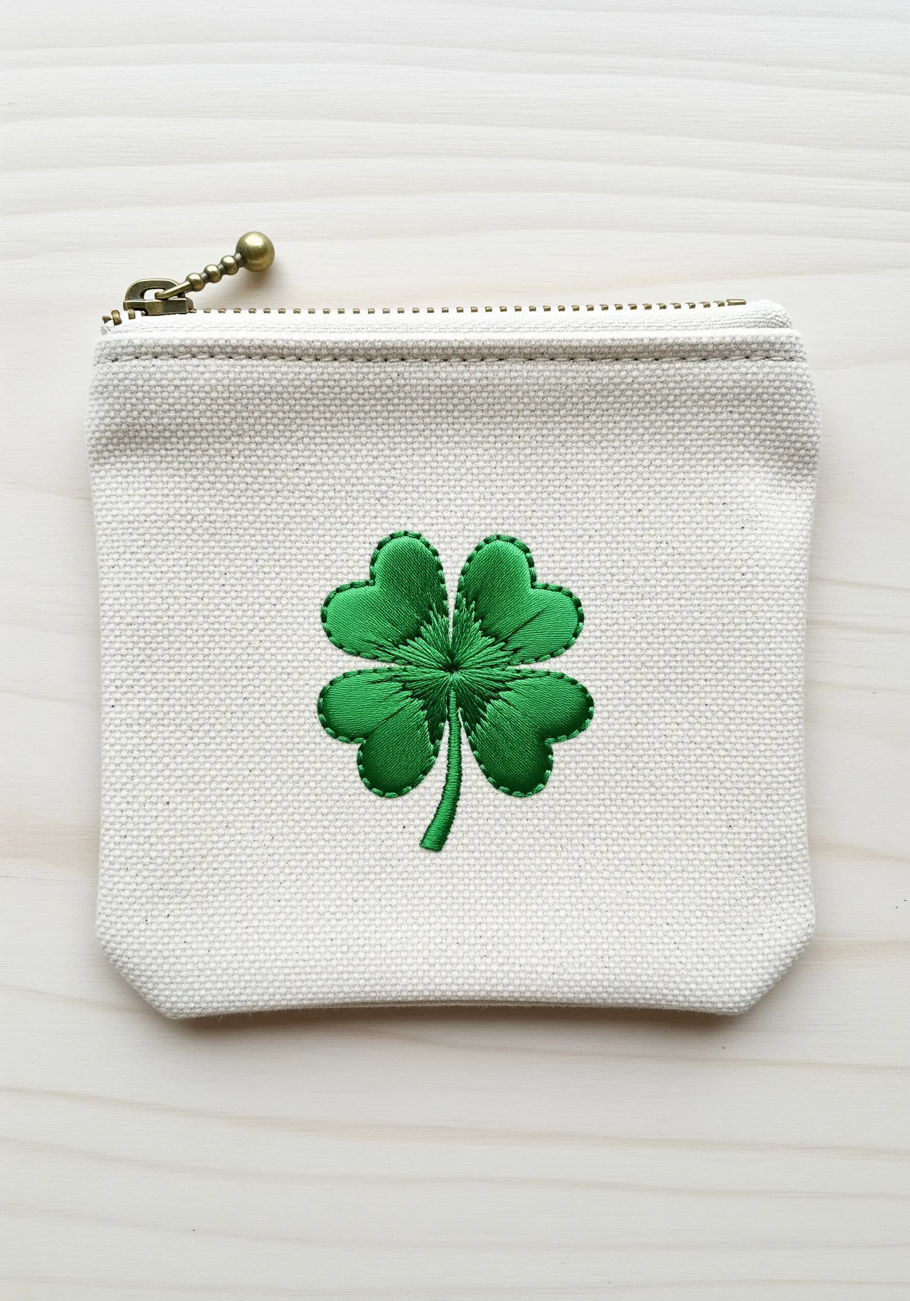 A four-leaf clover with dimensional satin stitch on a canvas zipper pouch.