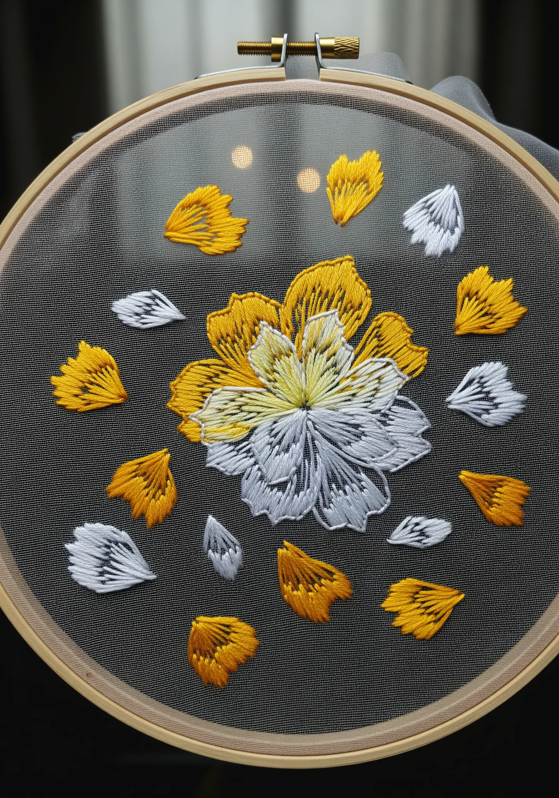An 'exploding' yellow and white flower with floating petals embroidered on sheer black fabric.