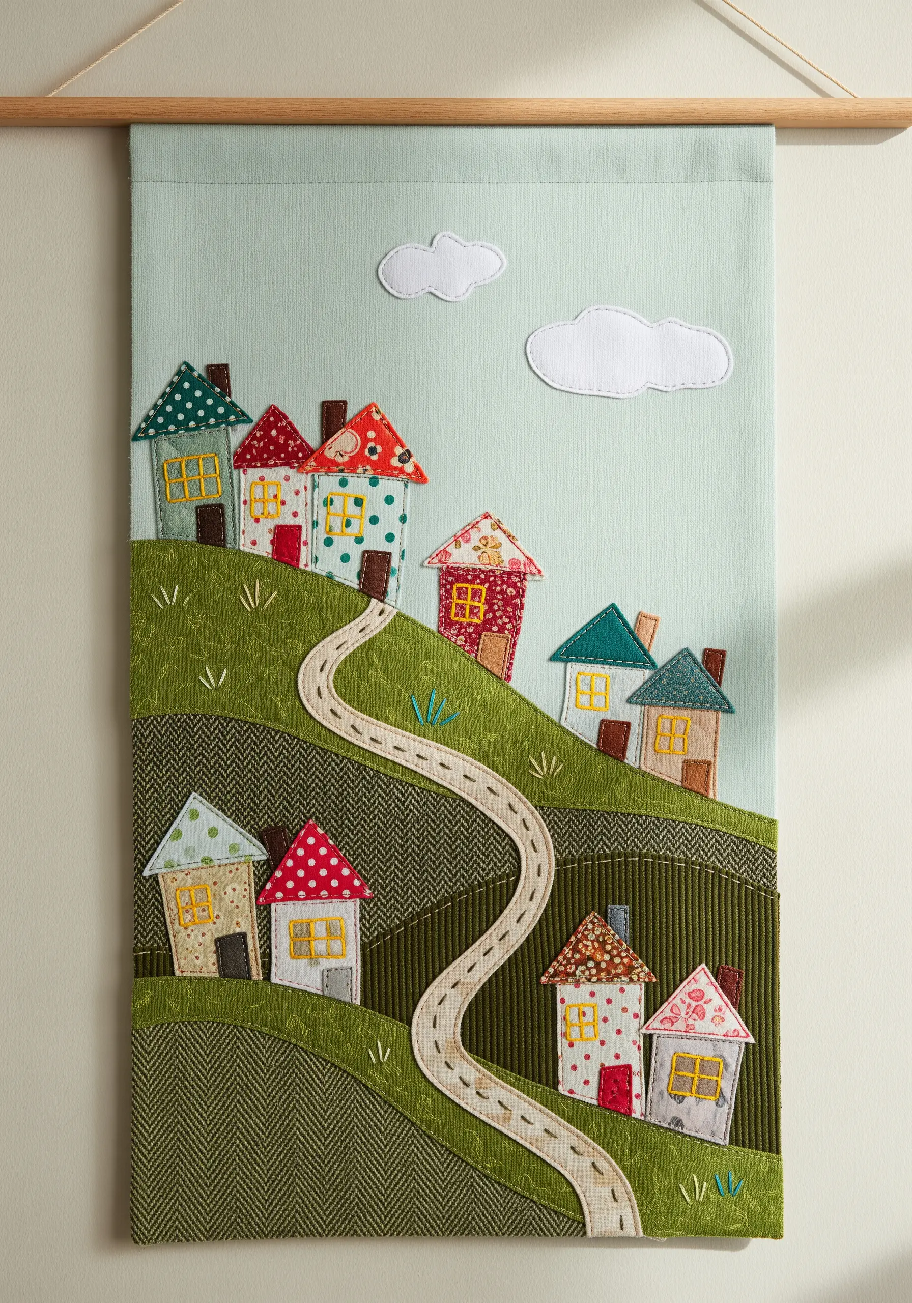 Fabric collage of a hillside village using corduroy and patterned fabric scraps