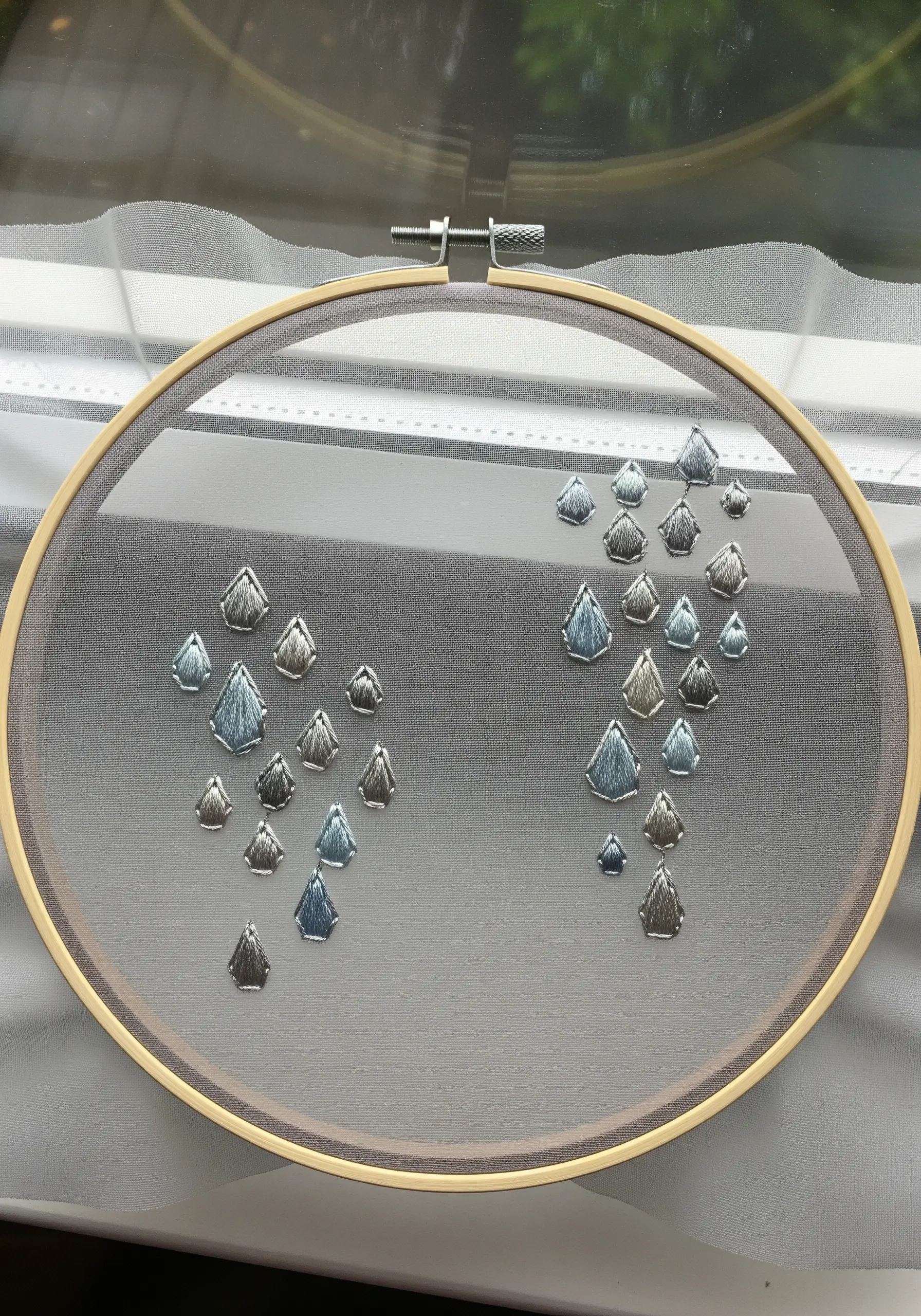 Silver and blue satin stitched teardrop shapes on sheer fabric.