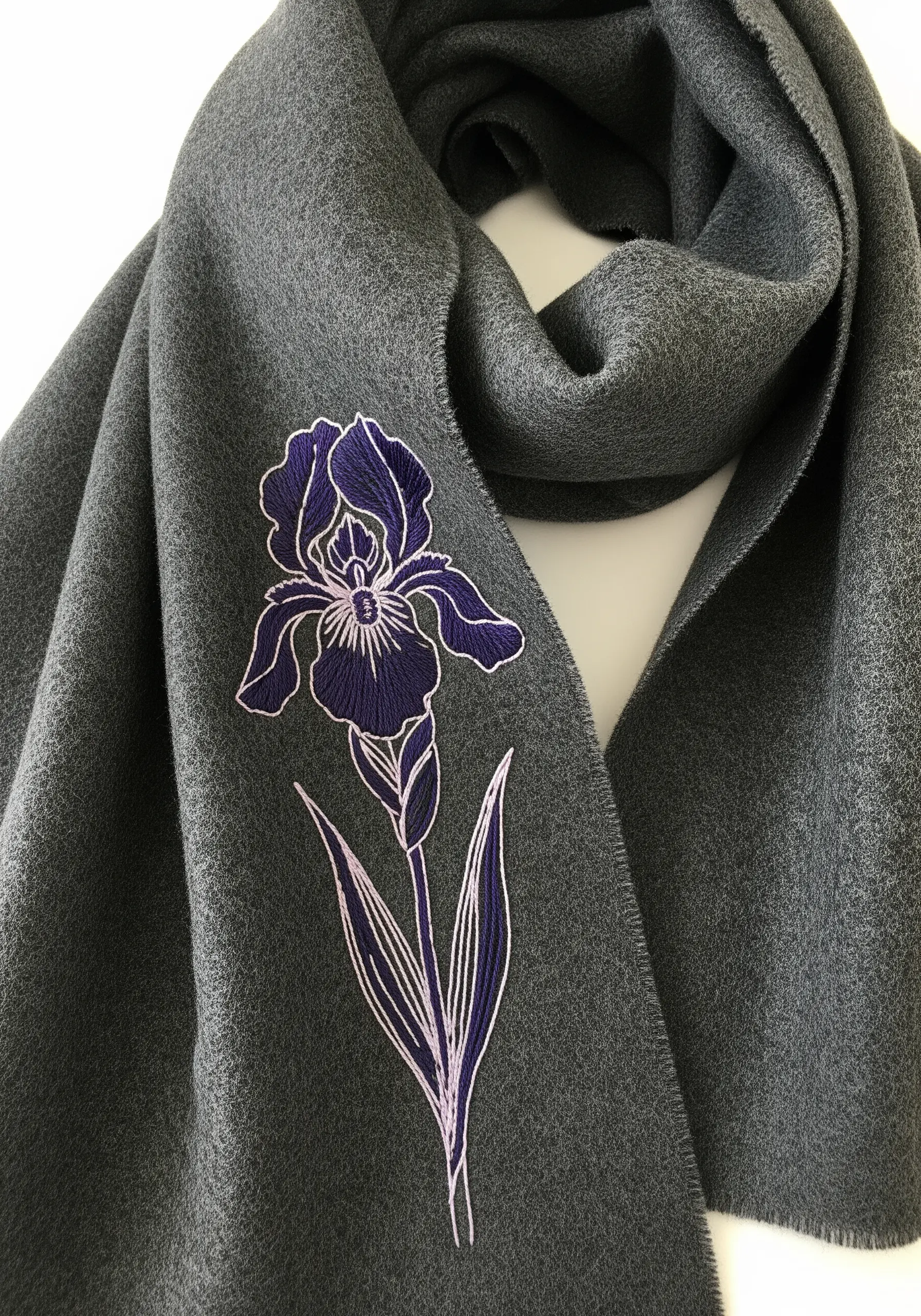 A stylized iris with purple and white outlines embroidered on a dark grey wool scarf.
