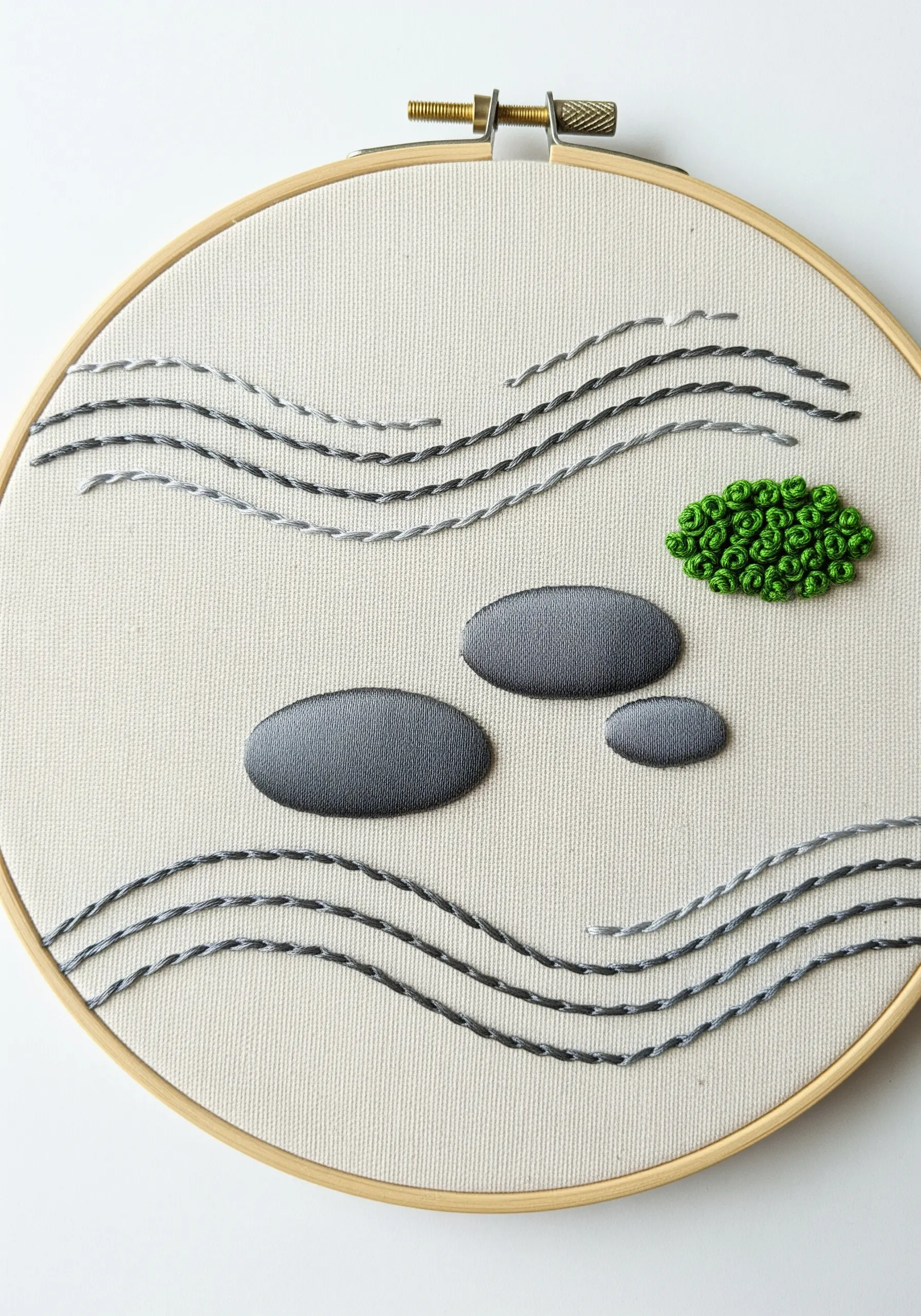 Minimalist Zen garden embroidery with padded satin stitch stones and whipped backstitch lines.