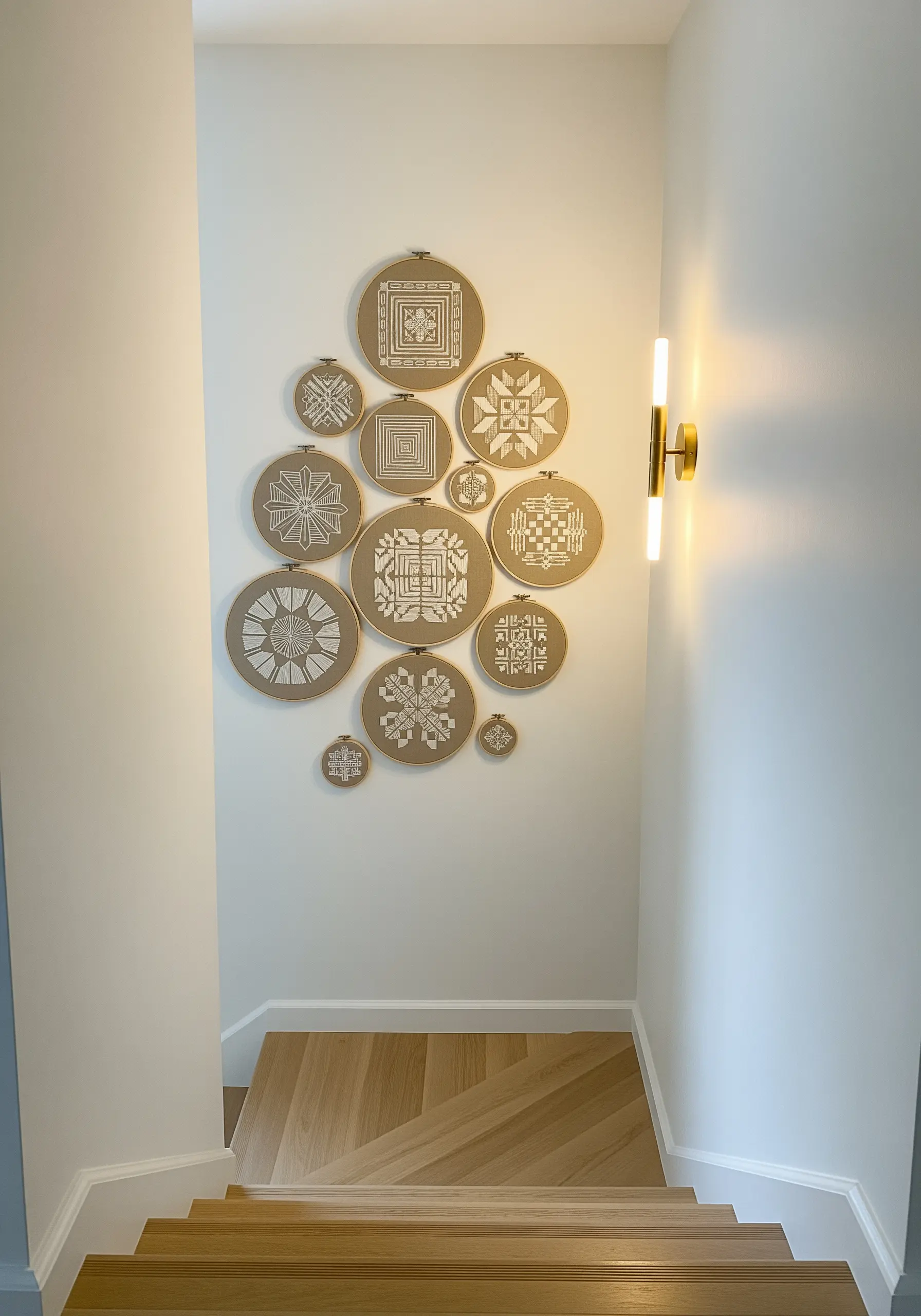 A gallery wall of embroidery hoops in various sizes with geometric white-on-sand patterns.