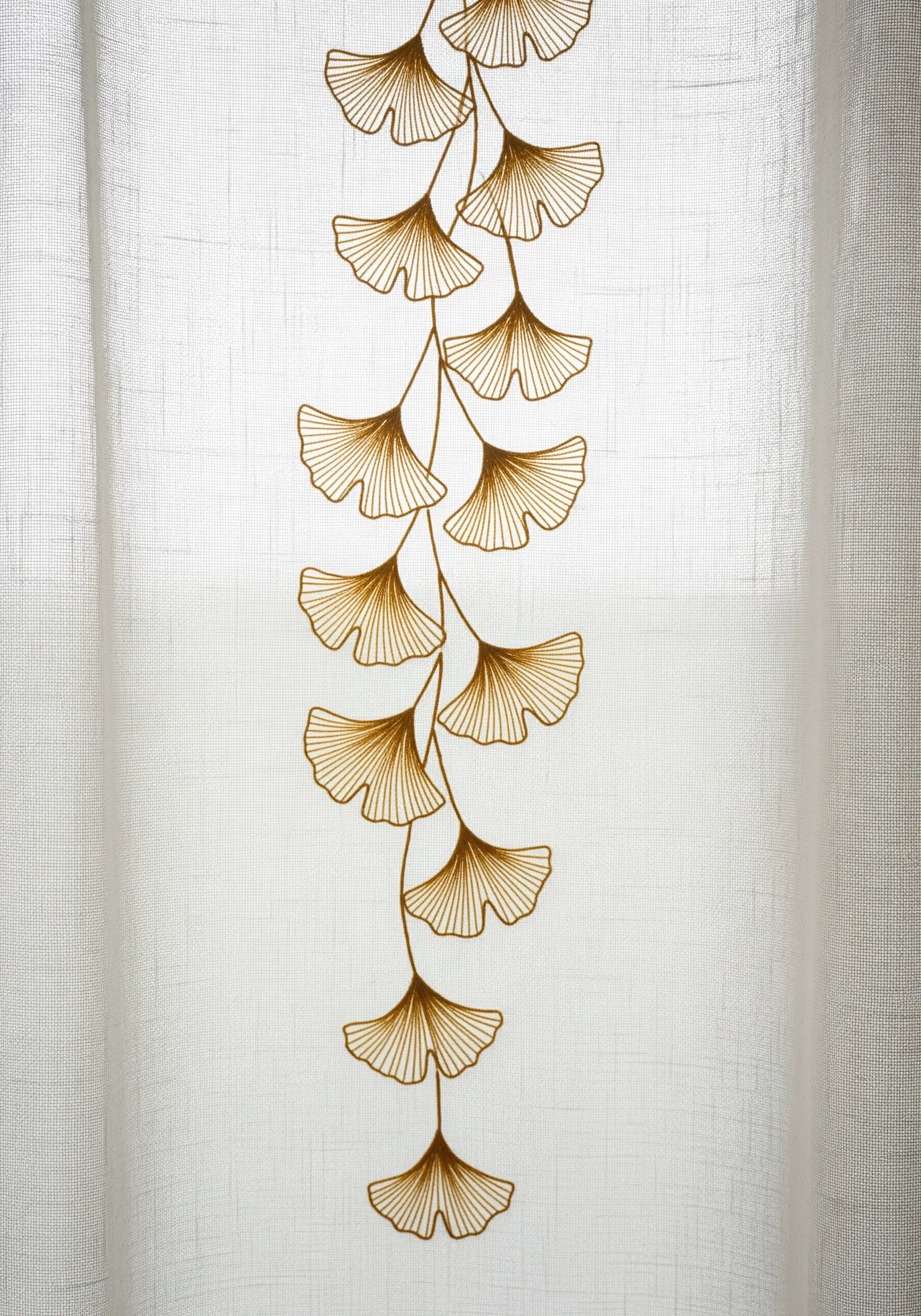 Gold thread embroidery of a ginkgo vine on a sheer white curtain.
