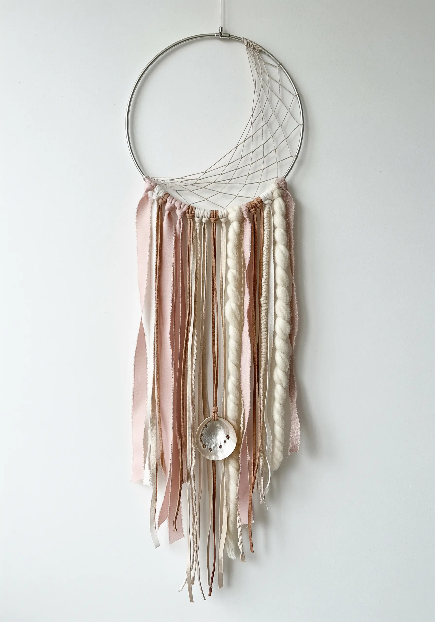 Modern dreamcatcher with a partial web and asymmetrical arrangement of pink ribbons and wool roving.