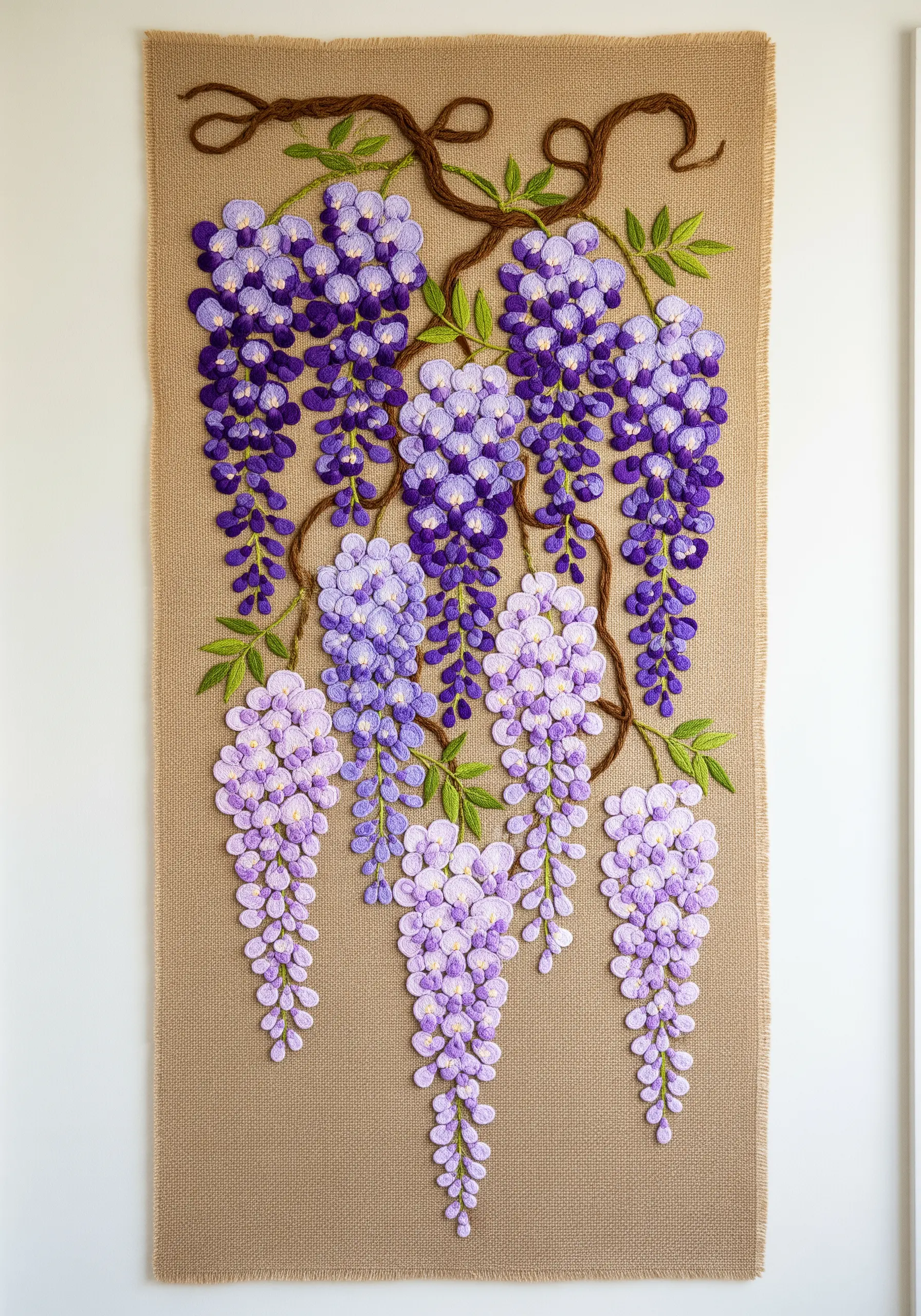A large wall tapestry of hanging wisteria blossoms, embroidered in gradients of purple on burlap.