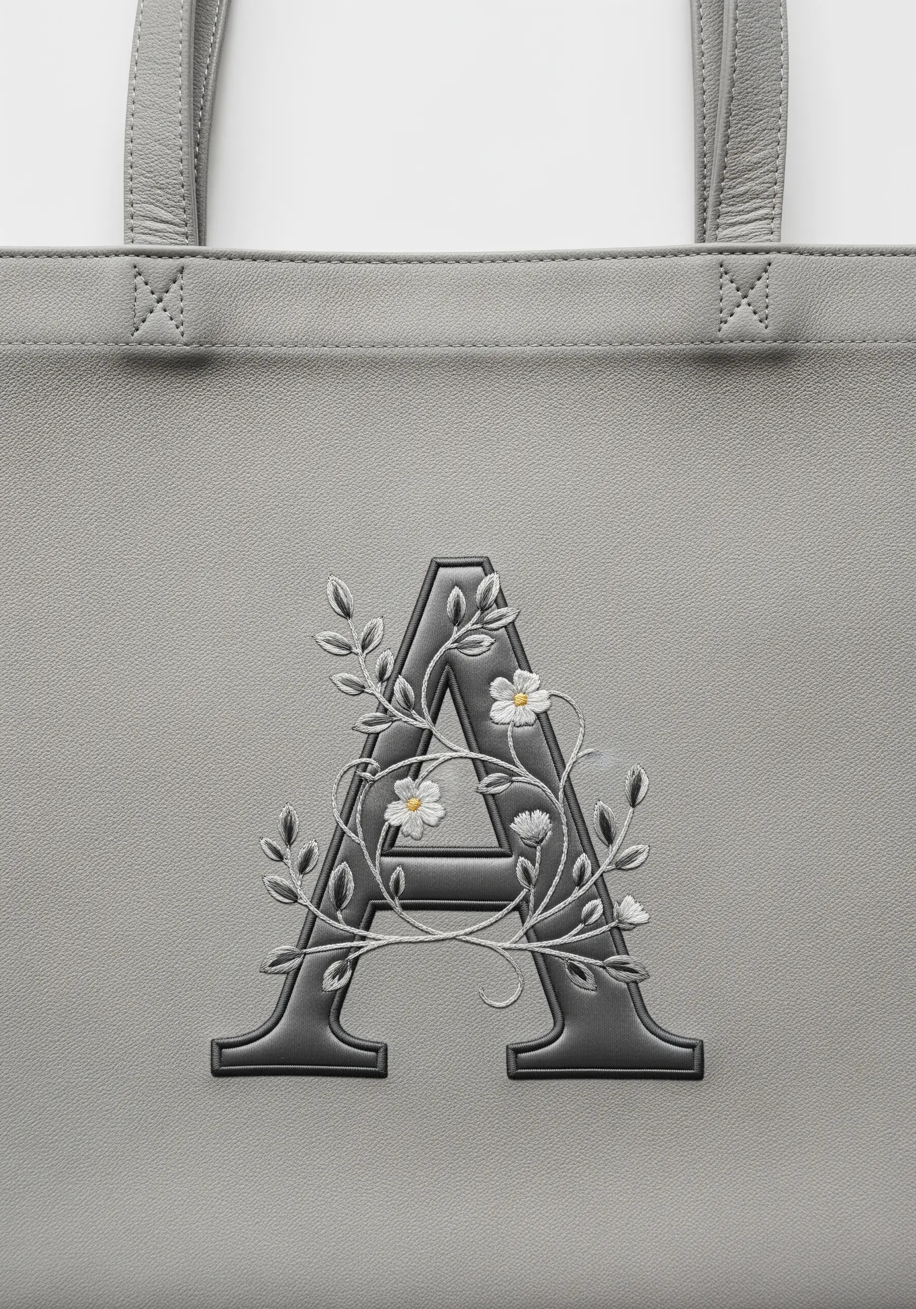 An elegant gray floral monogram embroidered in shades of gray on a gray leather tote