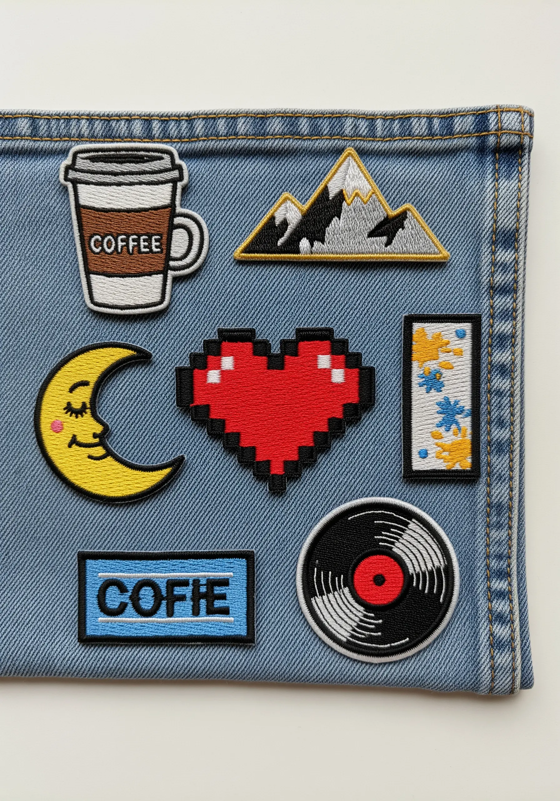 A collection of small, custom-made embroidered patches on a piece of denim.
